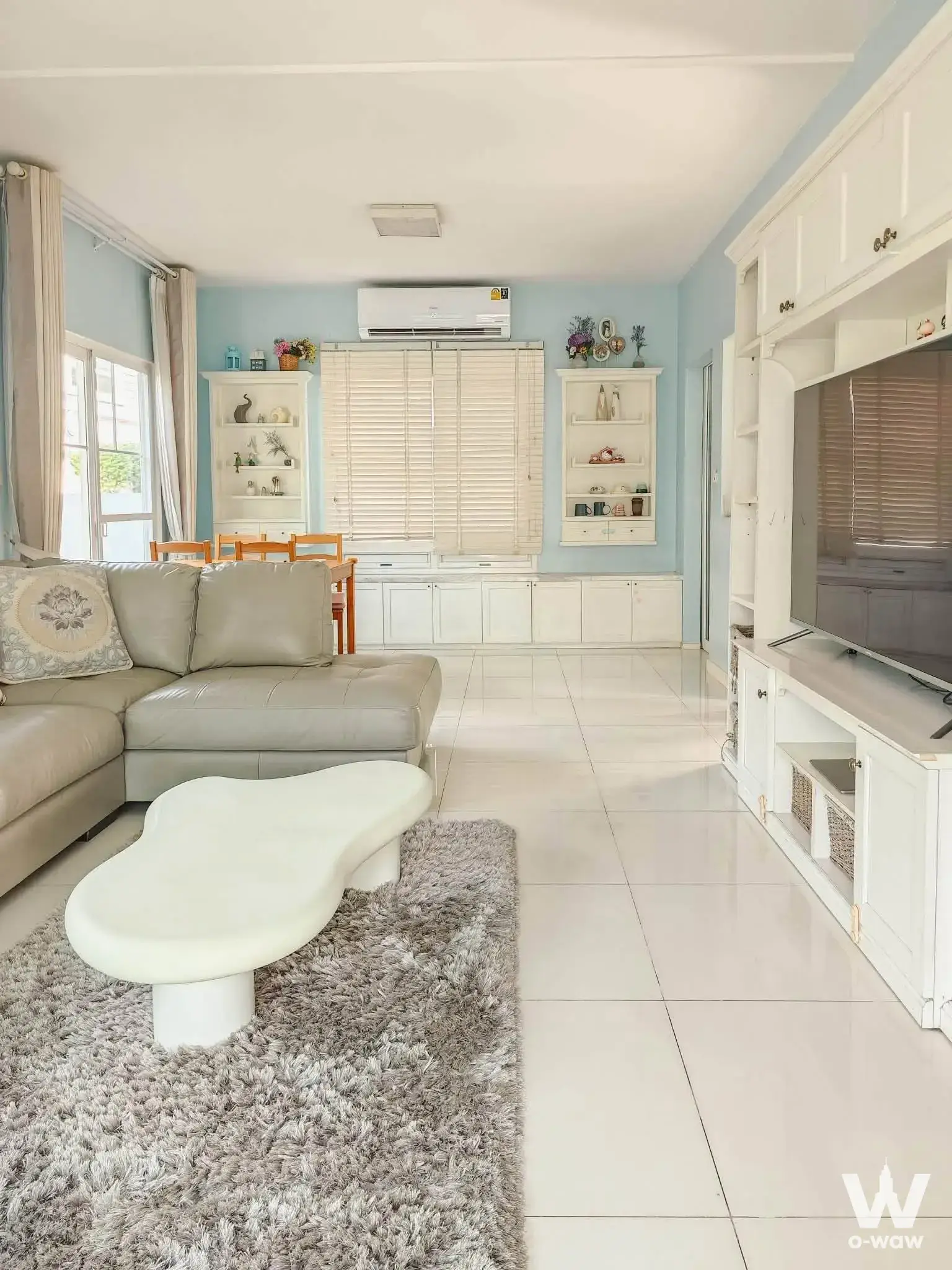 Bright living room in a Chaiyapruek 3-bed house featuring beige sectional sofa and cloud-shaped table