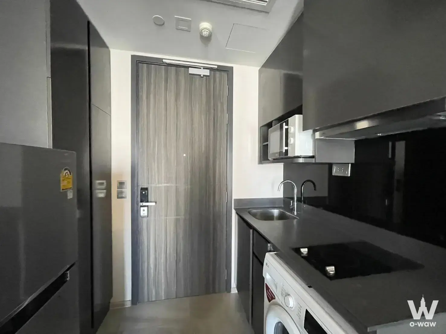 Galley kitchenette in an Ashton Asoke condo with dark grey cabinets and stainless steel appliances