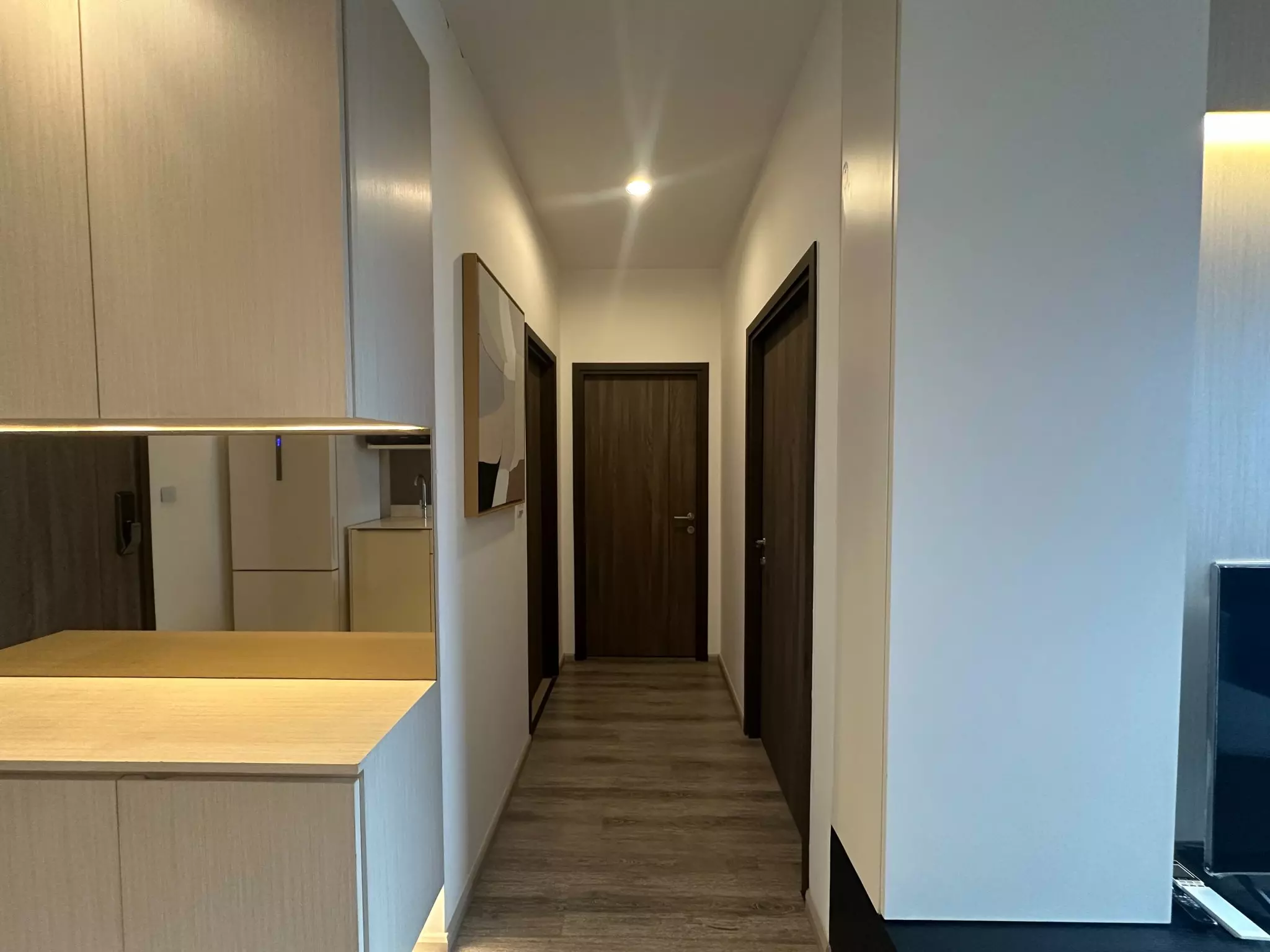 Hallway in Ideo Mobi Sukhumvit 66 featuring walnut doors and kitchen reflection