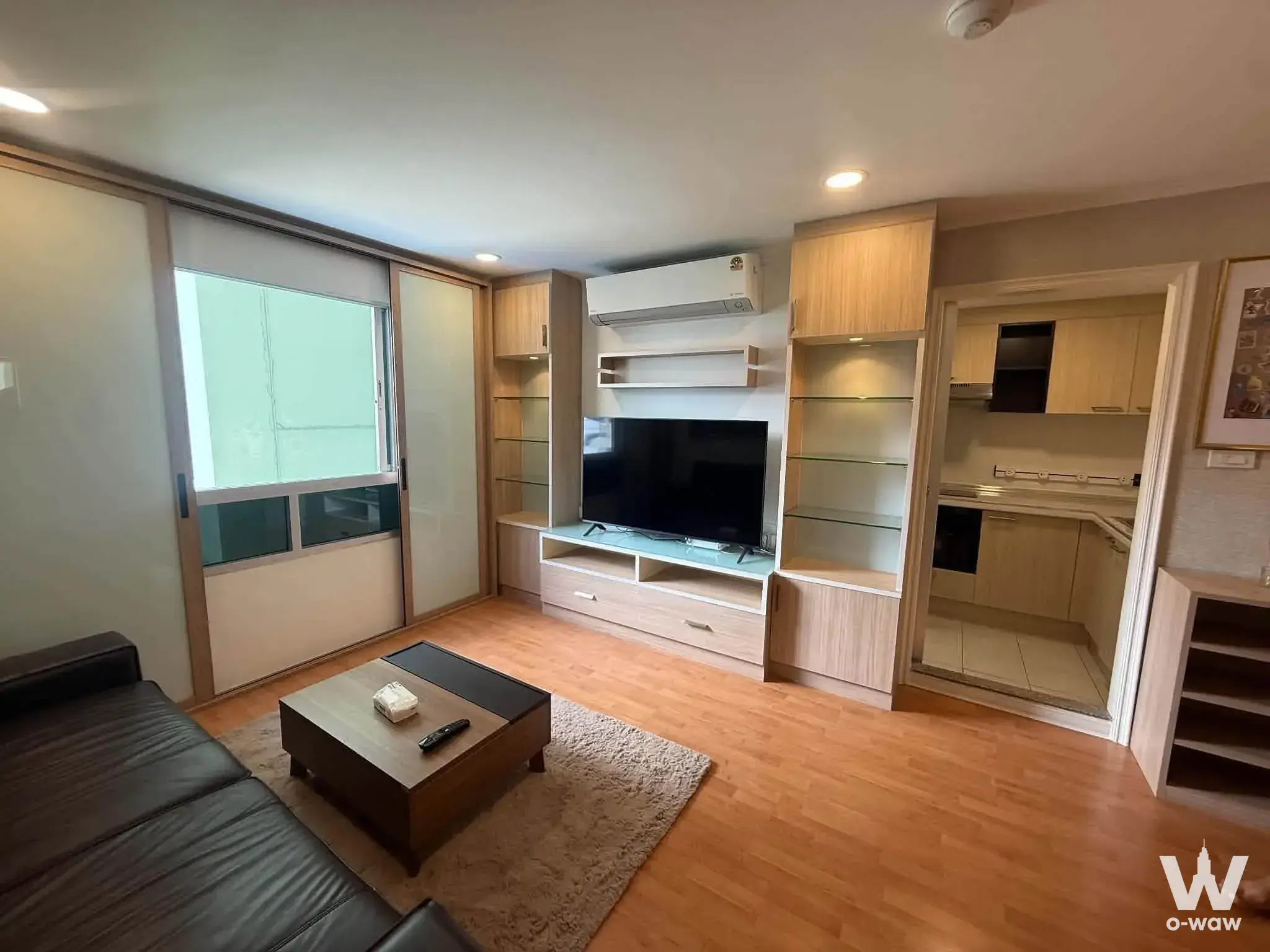 Modern living room with entertainment center and balcony access in a Lumpini Ville condo