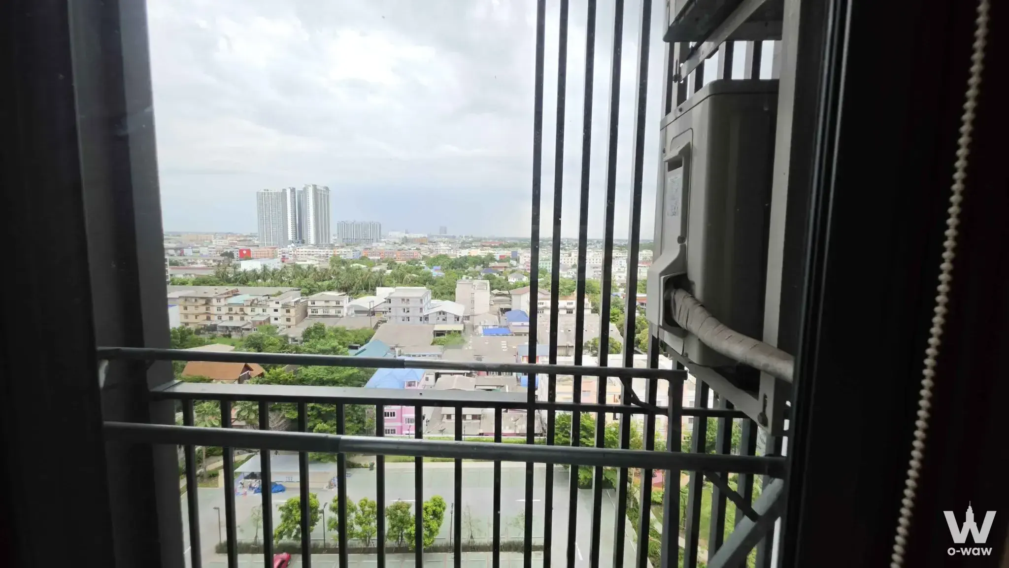 High-floor balcony view in The Parkland Phetkasem 56 condo showing city skyline and urban density through security bars