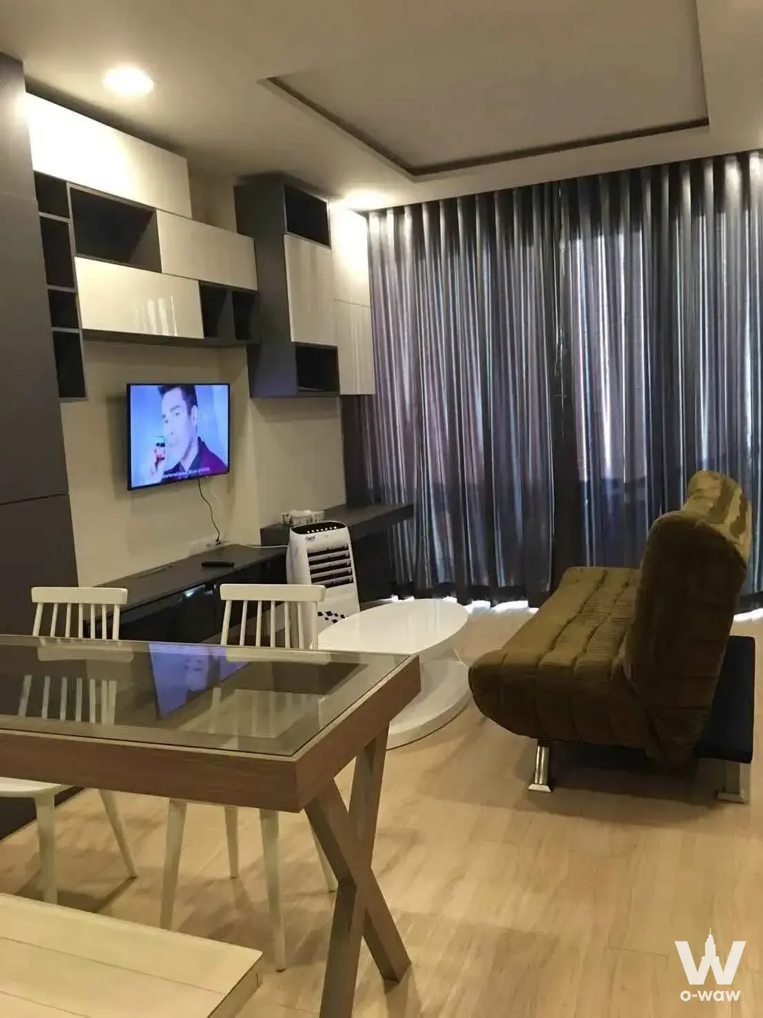 Living-dining room in a 1-bed Cetus Beachfront Pattaya condo with an olive sofa and floor-to-ceiling sheer curtains