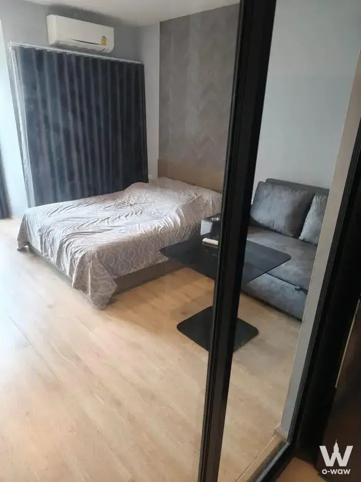 Ideo Sathon-Wongwian Yai bedroom with grey accent wall and lounge area