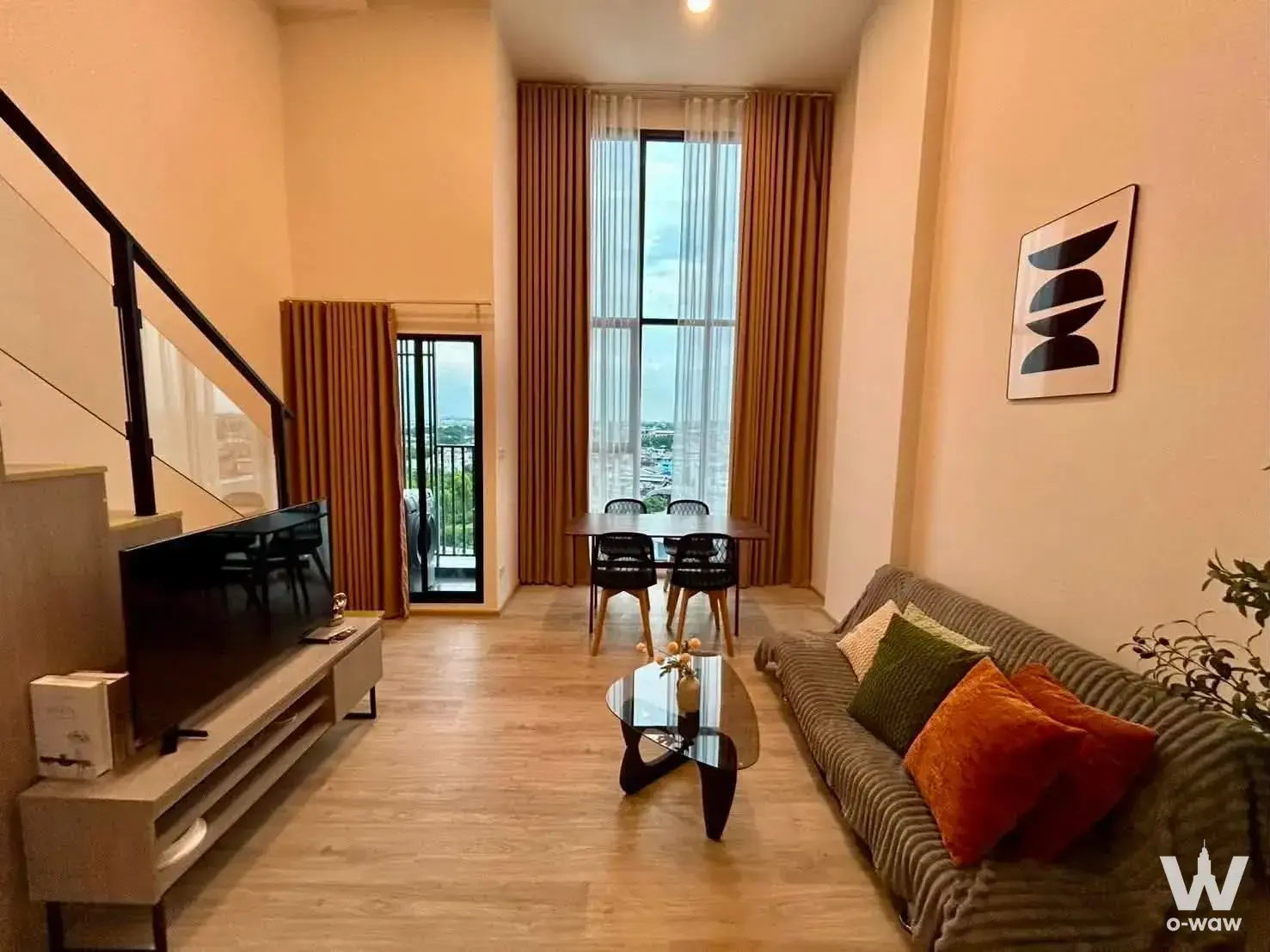 Open-plan living and dining area in a 1-bed condo for rent in SO Origin Phahol 69 Station with a grey sofa and glass table