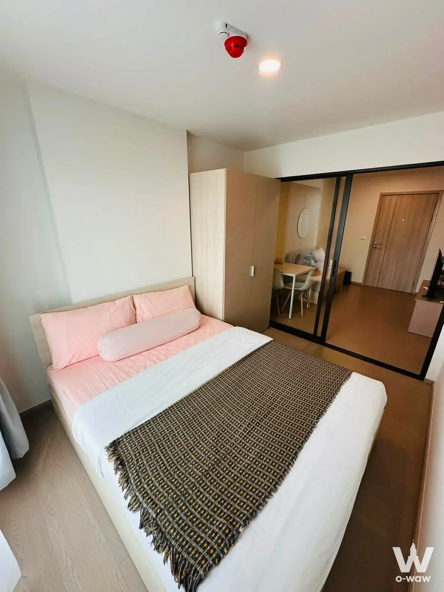 Furnished bedroom with pink bedding and sliding glass partition in a 1-bed studio condo for rent at GOOD DAY Sukhumvit 93