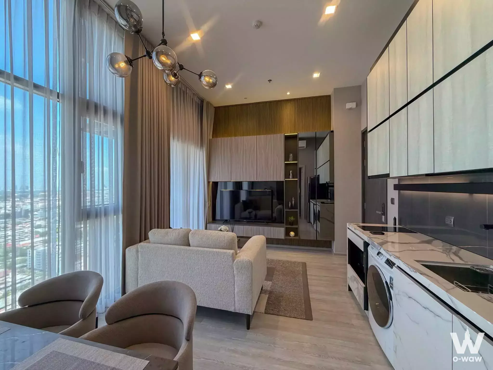 THE LINE Sukhumvit 71 open-plan living room with chandelier, media wall, and city views