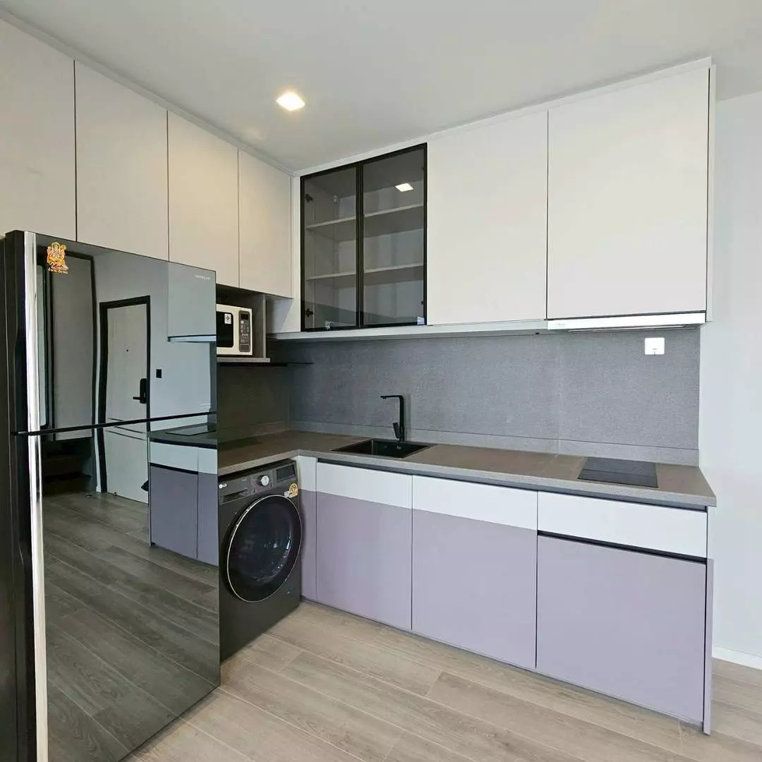 Modern kitchen in a 2-bed condo for sale in The Key Rama 3 with white cabinets, grey counters, and stainless fridge