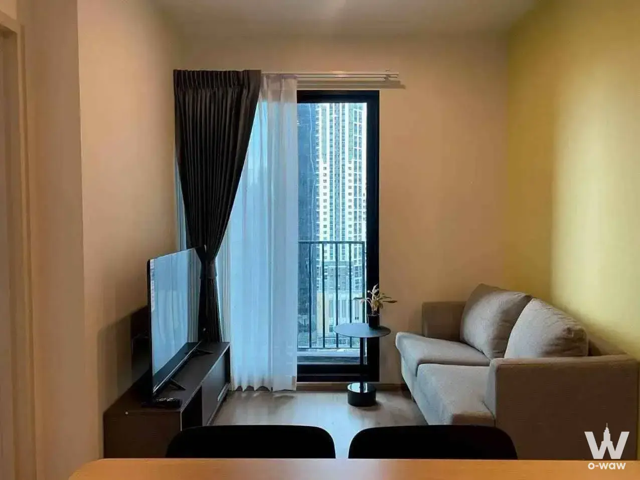 Modern 2-bed condo living room in Nue District R9 with grey sofa and balcony access