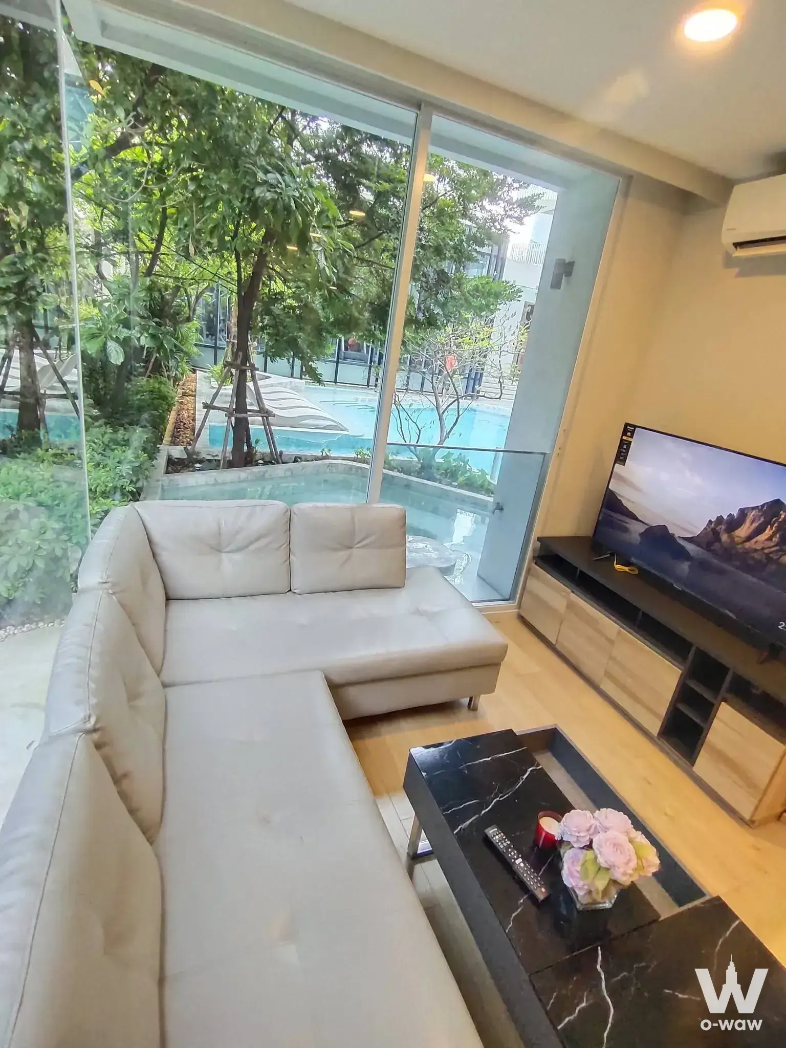 Cream leather sectional and marble table in the Chewathai Residence Thong Lo living room overlooking a blue pool