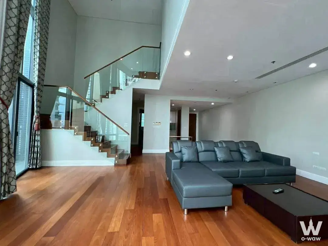 High-ceiling loft living room with dark grey sectional and hardwood floors in a 3-bed Bright Sukhumvit 24 rental