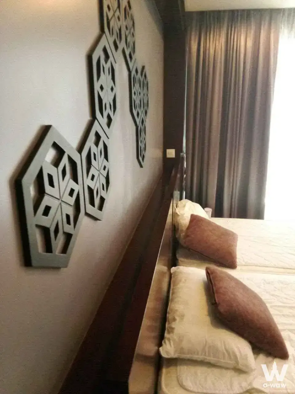 Twin beds with dark wood headboard and hexagonal wall art in this 1-bed for sale at The Regent