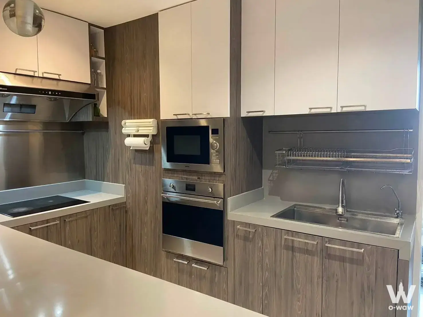 Modern kitchen in a Royal Castle Sukhumvit condo with wood-grain cabinets and stainless steel appliances