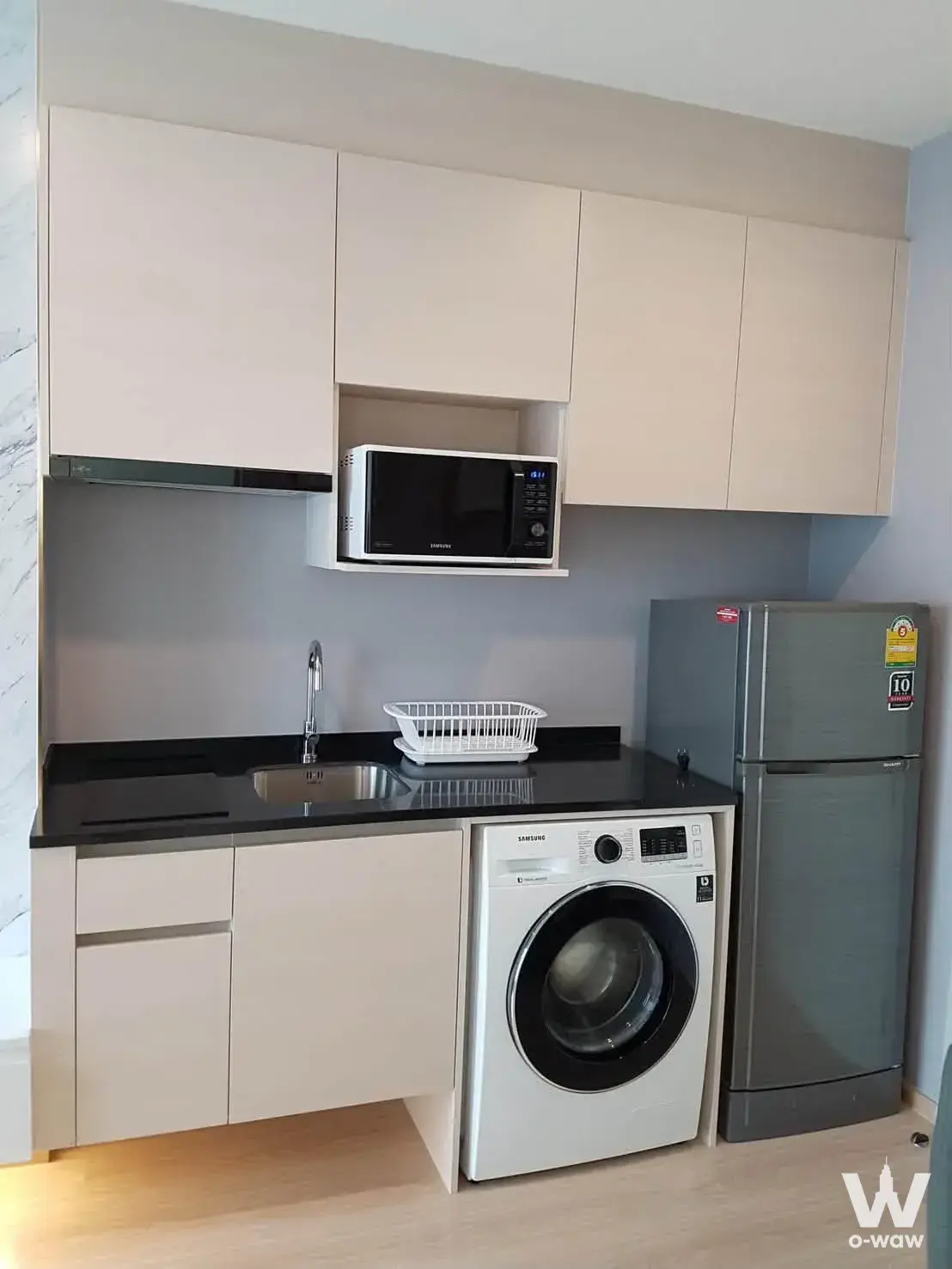 Compact kitchenette in Noble Revolve Ratchada 2 featuring beige cabinets and integrated Samsung appliances