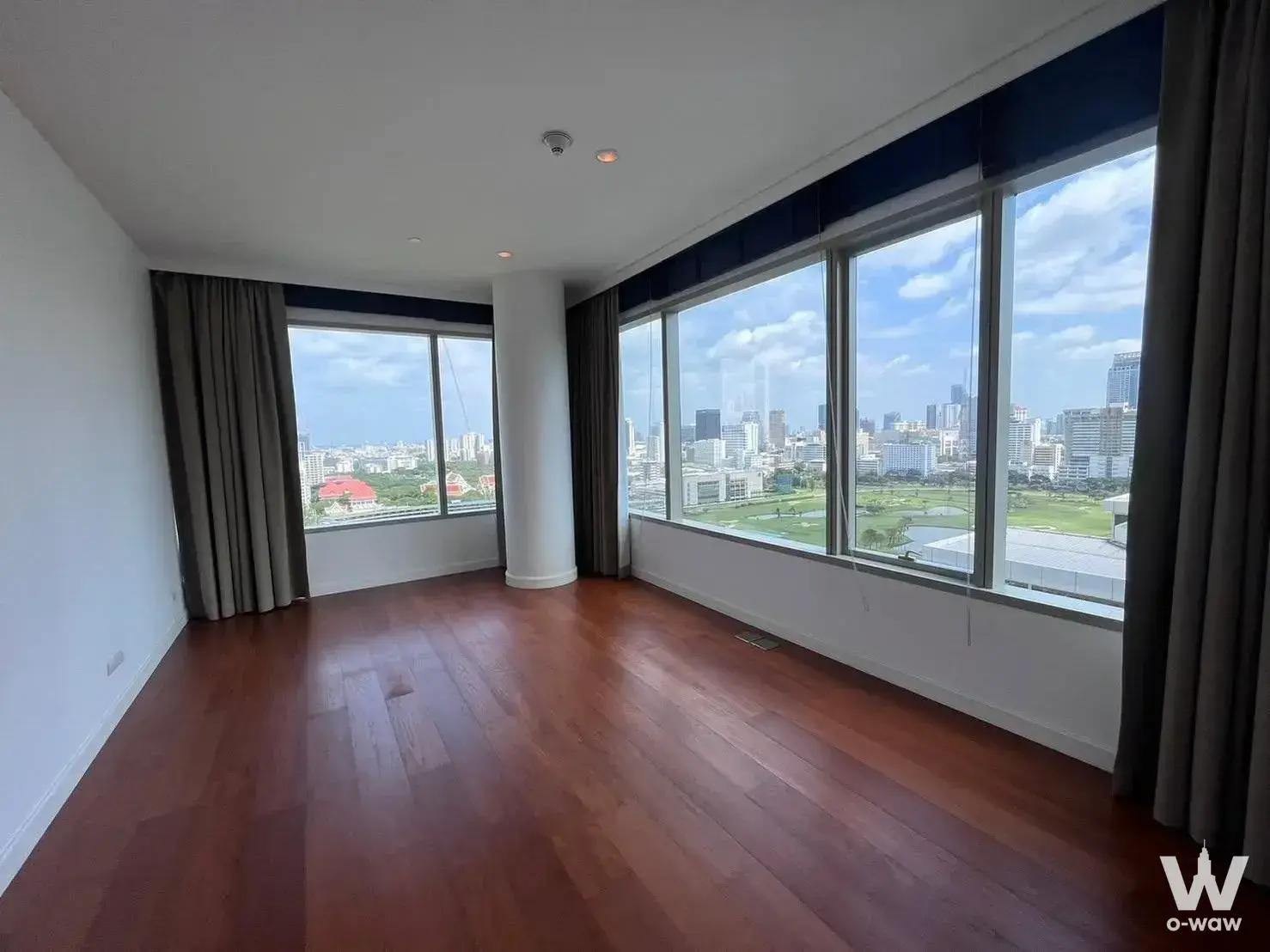 Empty 3-bed condo living room in 185 Rajadamri with reddish-brown floors and park views