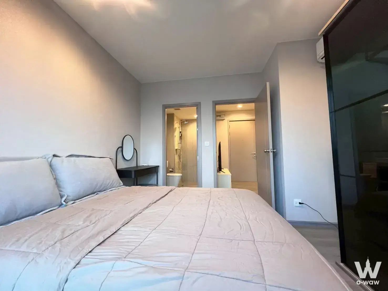 Furnished bedroom in The Politan Aqua condo featuring a queen bed, console table, and glass wardrobe panel