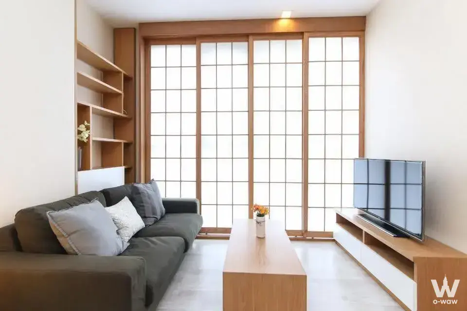 Bright living room in IDEO Mobi Sukhumvit Tower B with dark sofa and floor-to-ceiling glass doors