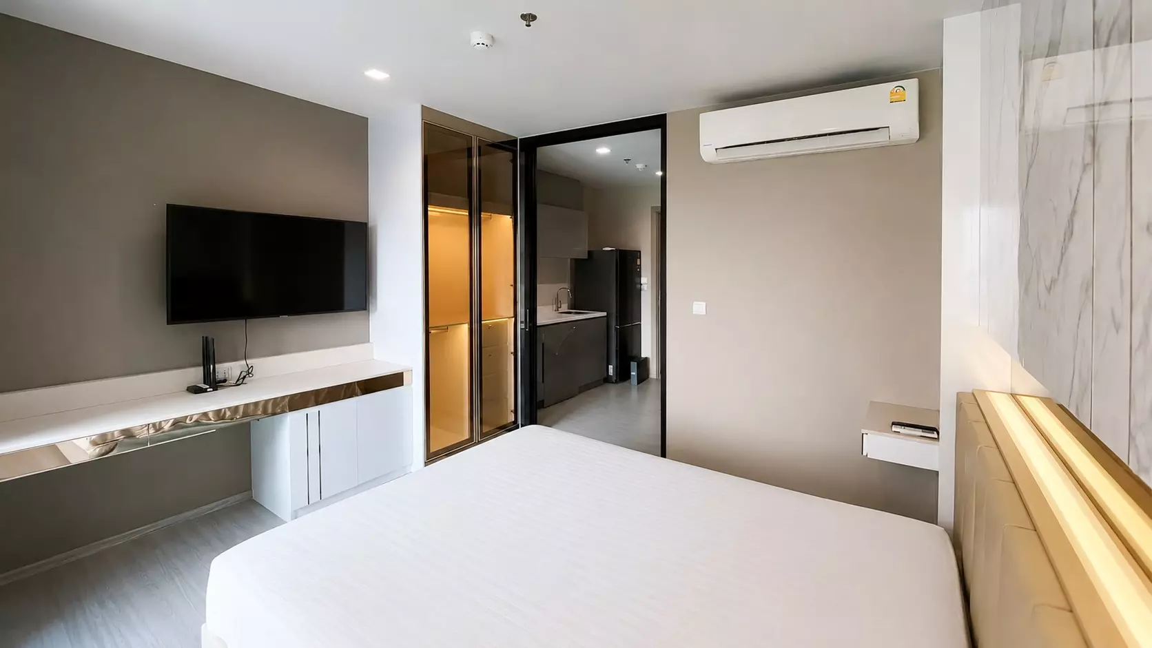 Bedroom in a Life Asoke condo for sale with beige leather headboard, floating desk, and mirrored wardrobe doors