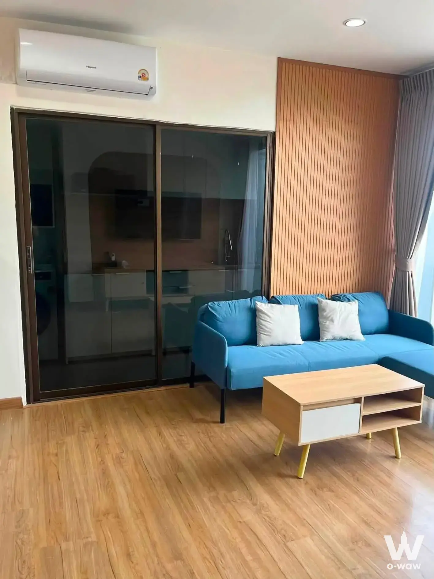 The Tree Bang Po Station 2-bed condo living room featuring blue sectional sofa and wood slat wall