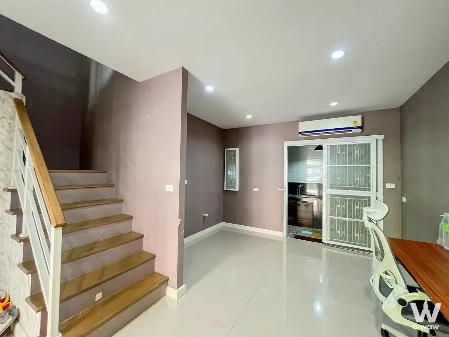 Open-plan ground floor living area in a Willet Light townhouse with staircase, mauve-grey walls, and kitchen access