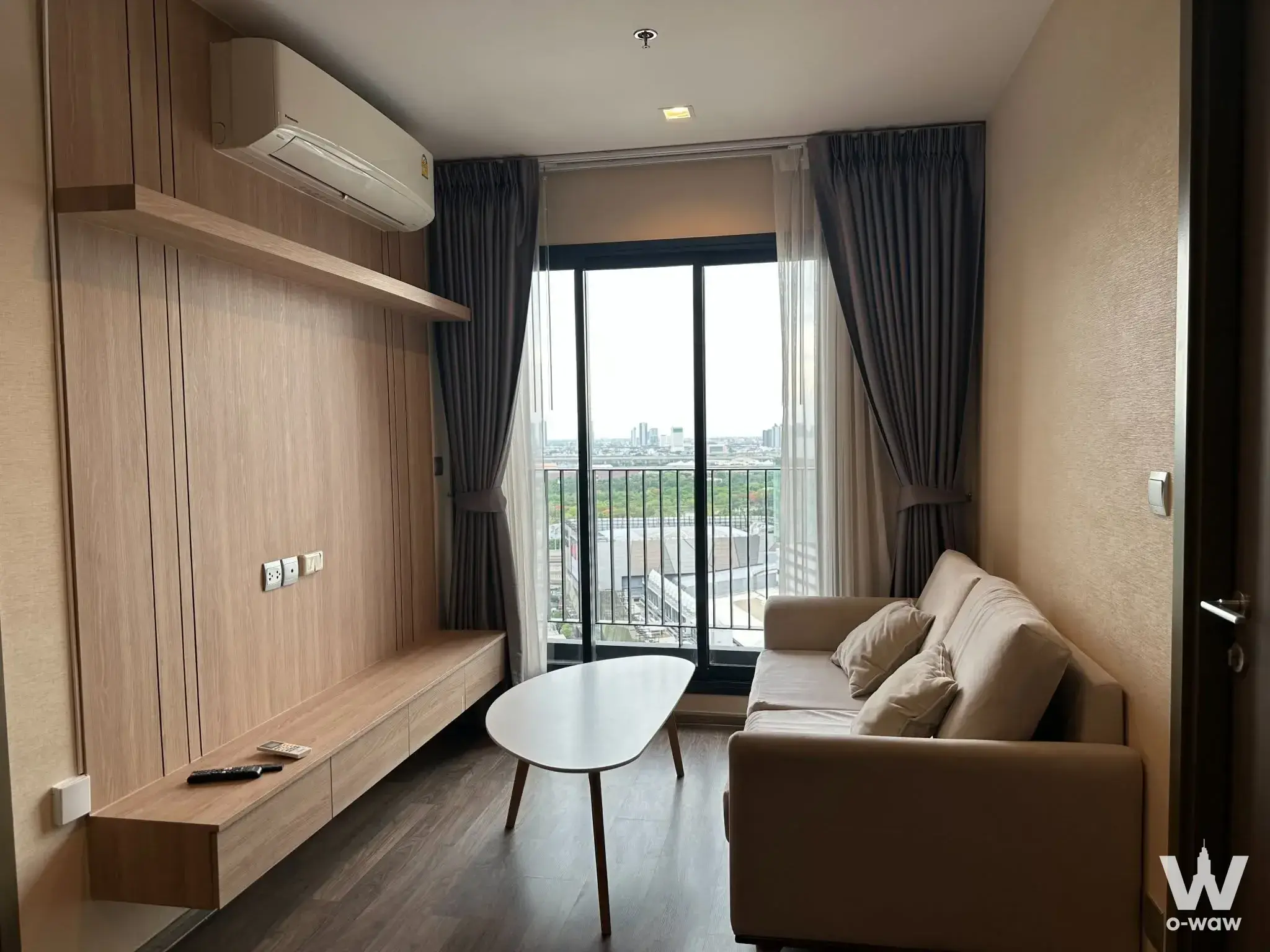 Furnished living room in a 2-bed Life Ladprao Valley condo with oak slat walls and balcony access