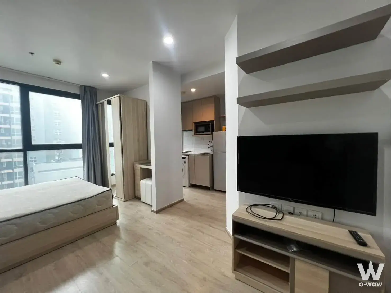The open-plan studio in a 1-bed Ideo Q Chula-Samyan condo features a platform bed, city view, and light wood kitchen