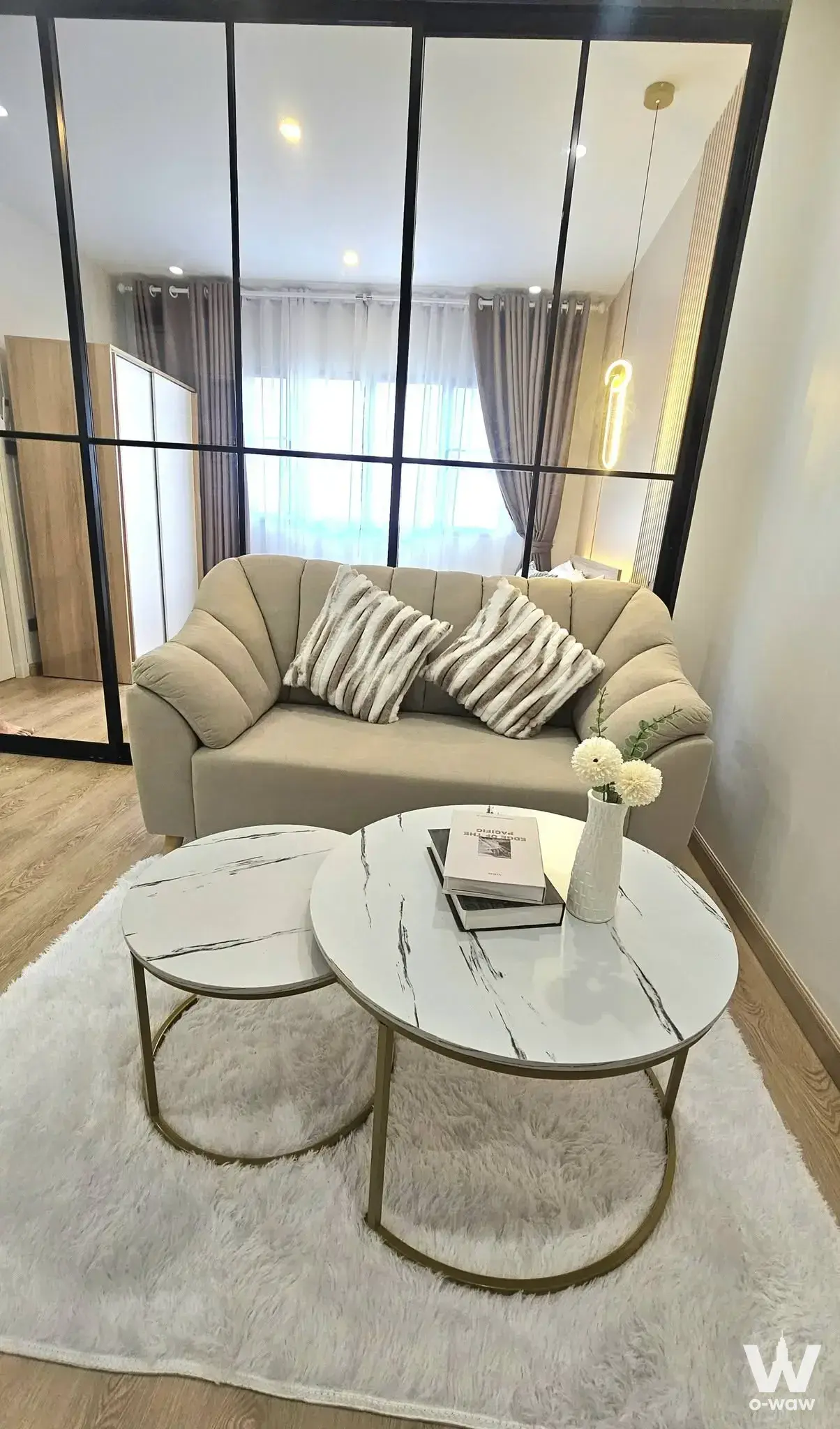 1-bed condo for sale in Lumpini Center Lat Phrao 111 displaying a living room separated from the bedroom by a glass grid wall