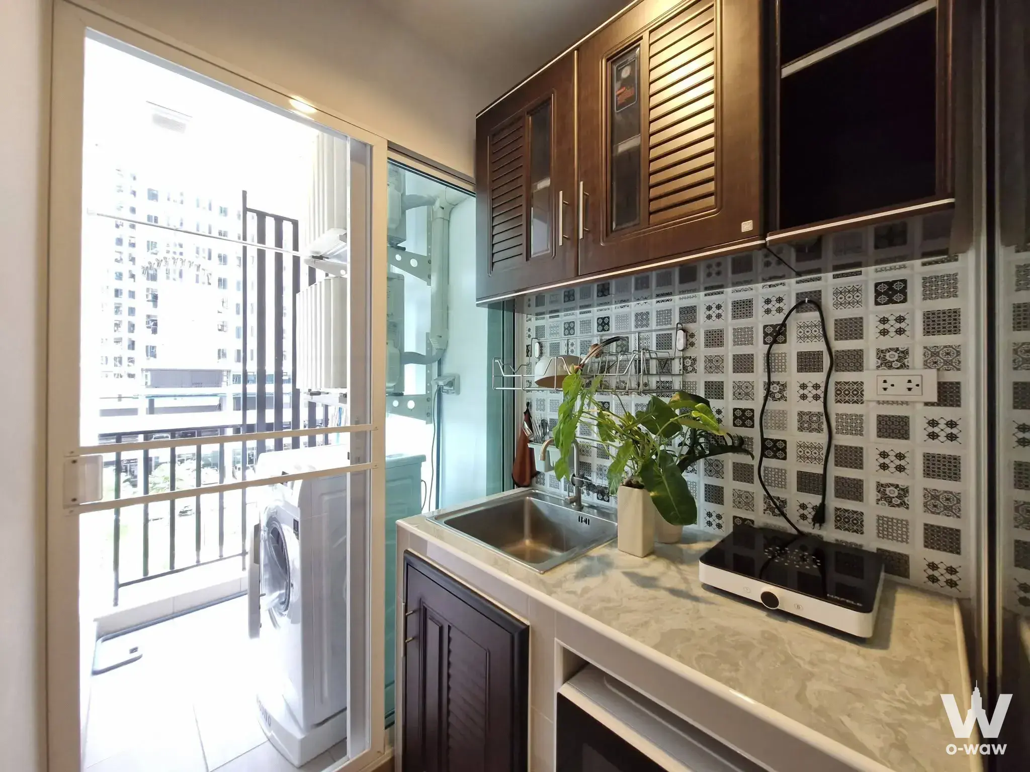 1-bed condo for rent in Regent Home Bangna showing a utility kitchen with dark wood cabinets and balcony access