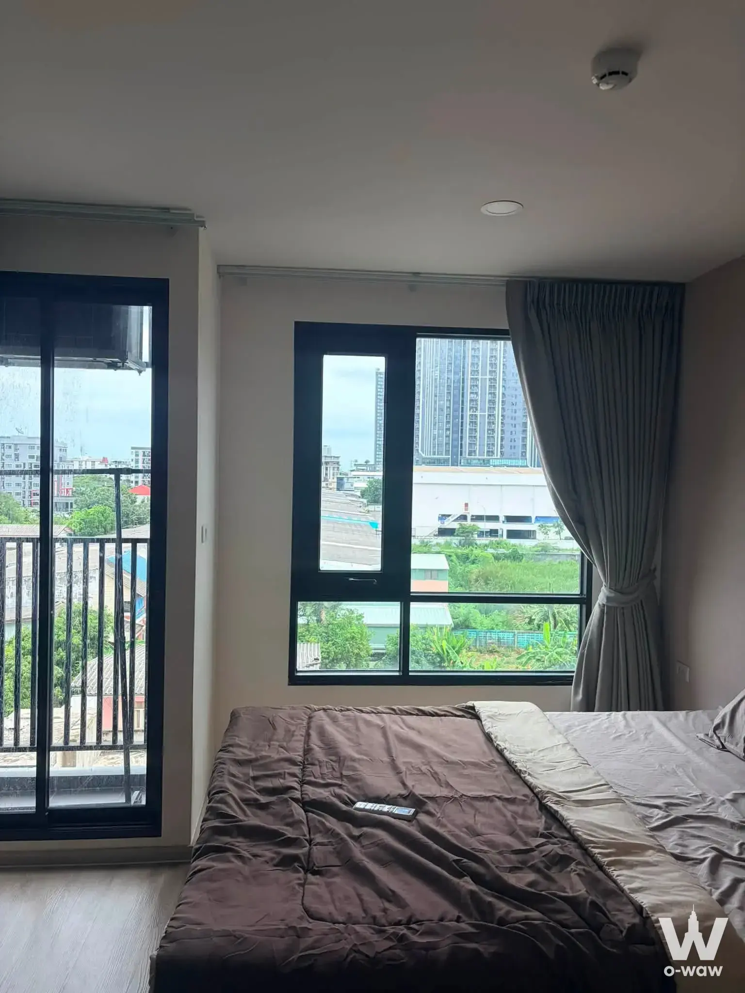 Bedroom with dark comforter and balcony access in a pet-friendly 1-bed Brompton Samrong Station condo