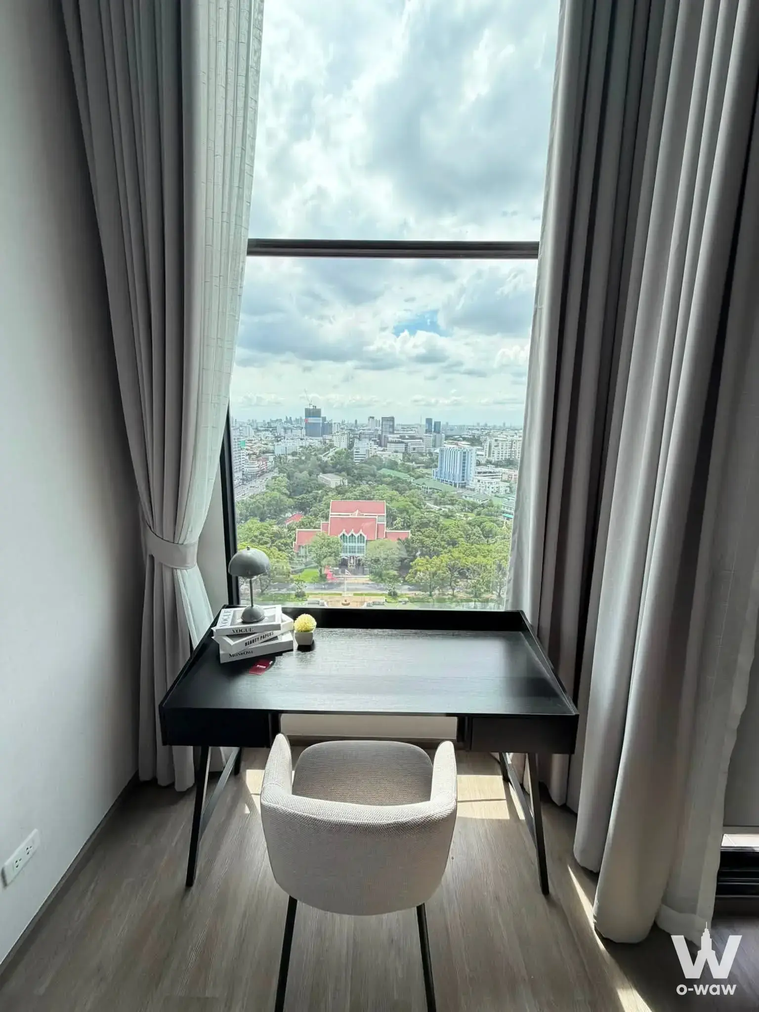Minimalist workspace in So Origin Kaset Interchange featuring a bucket chair and expansive park view