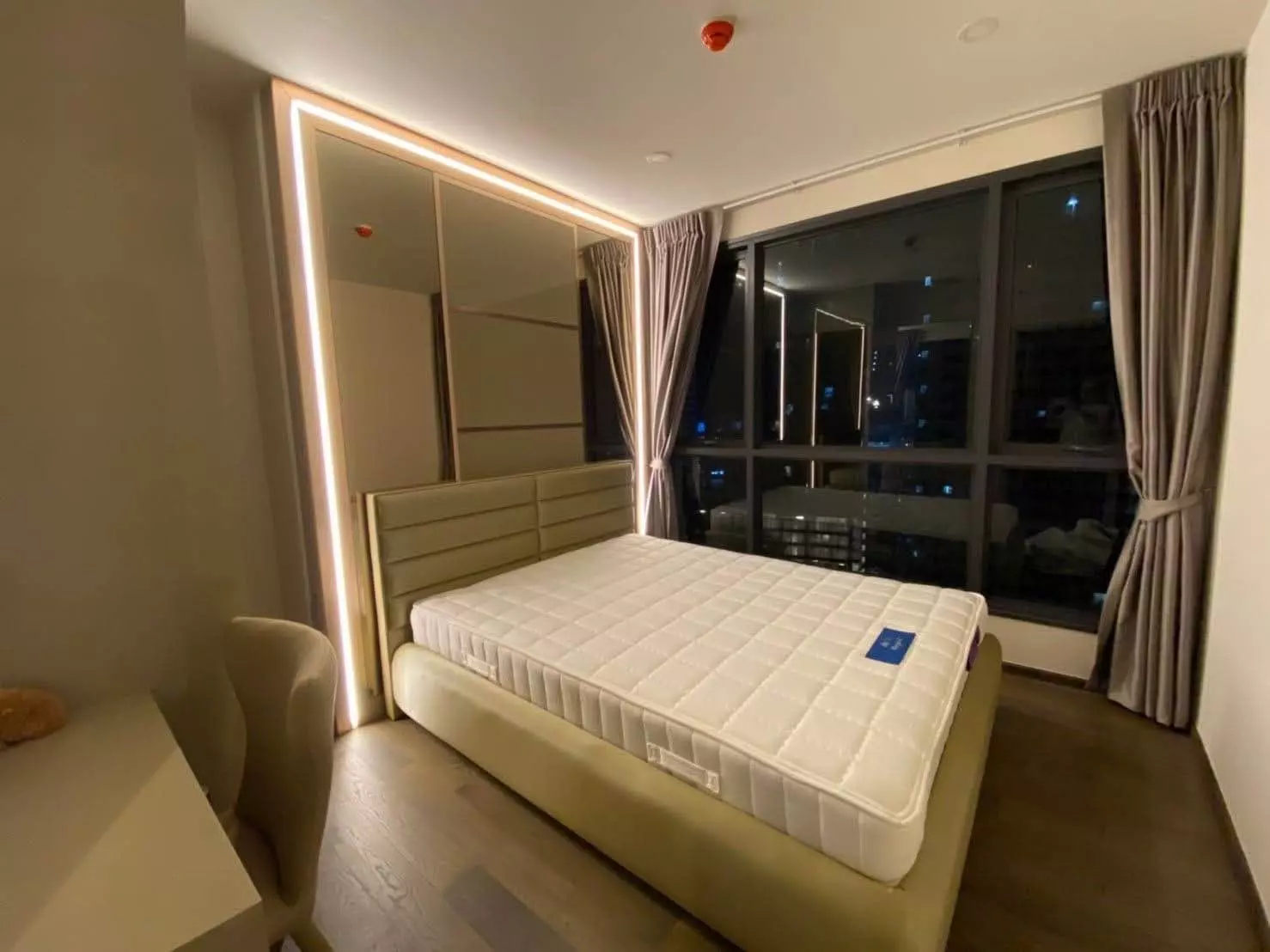 Queen bed with beige headboard and mirrored wardrobe in this 2-bed Ideo Q Siam-Ratchathewi condo