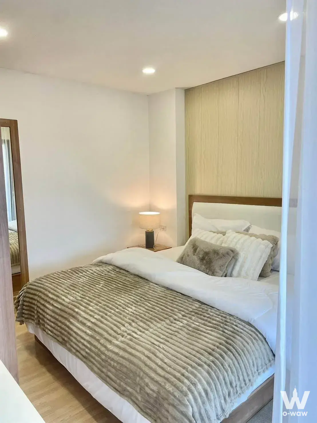 Queen bed with dark wood frame and vertical light-wood paneling in this Siri Place Airport Phuket townhouse