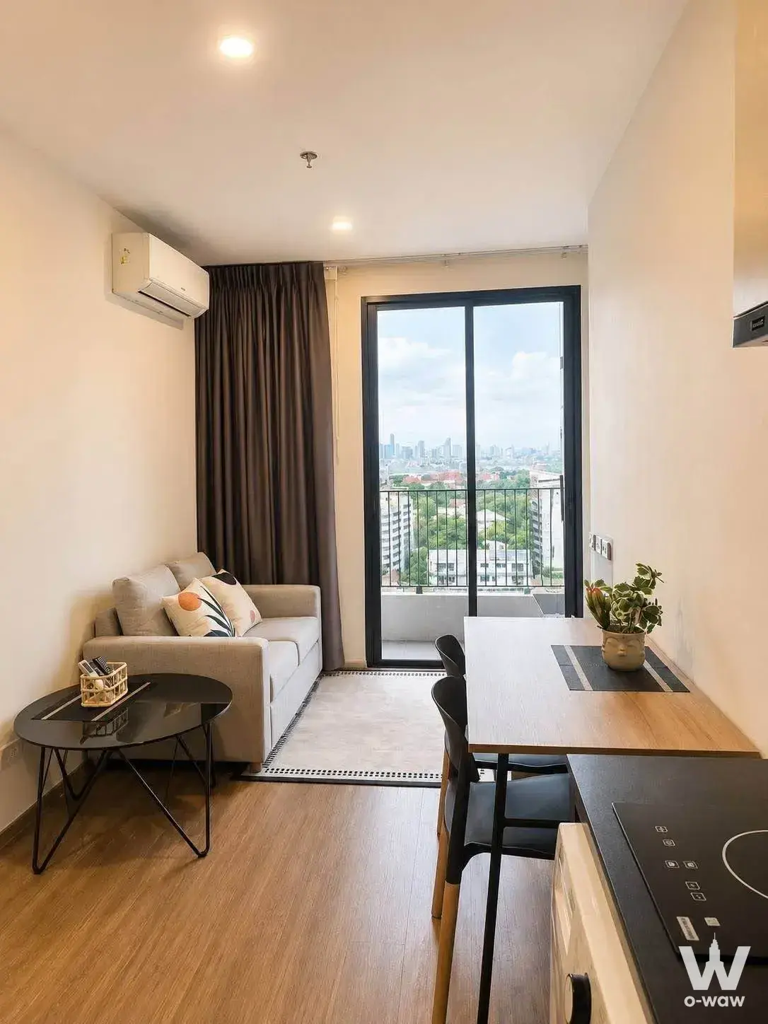 Living area with beige sofa and sliding glass doors to balcony in The LIVIN Phetkasem 1-bed condo for rent
