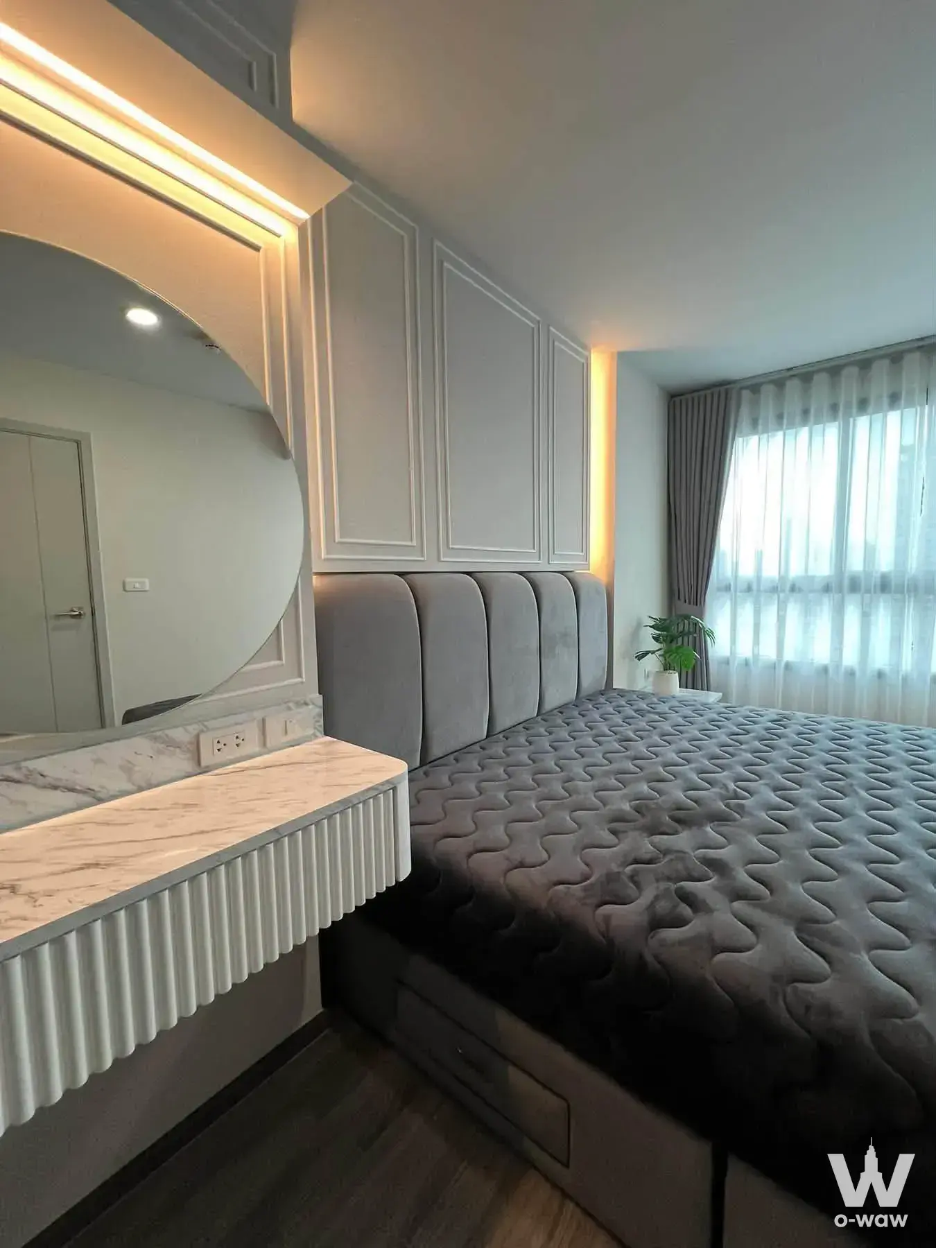 IDEO Chula-Sam Yan 1-bed condo master bedroom with grey velvet headboard, fluted vanity, and warm lighting