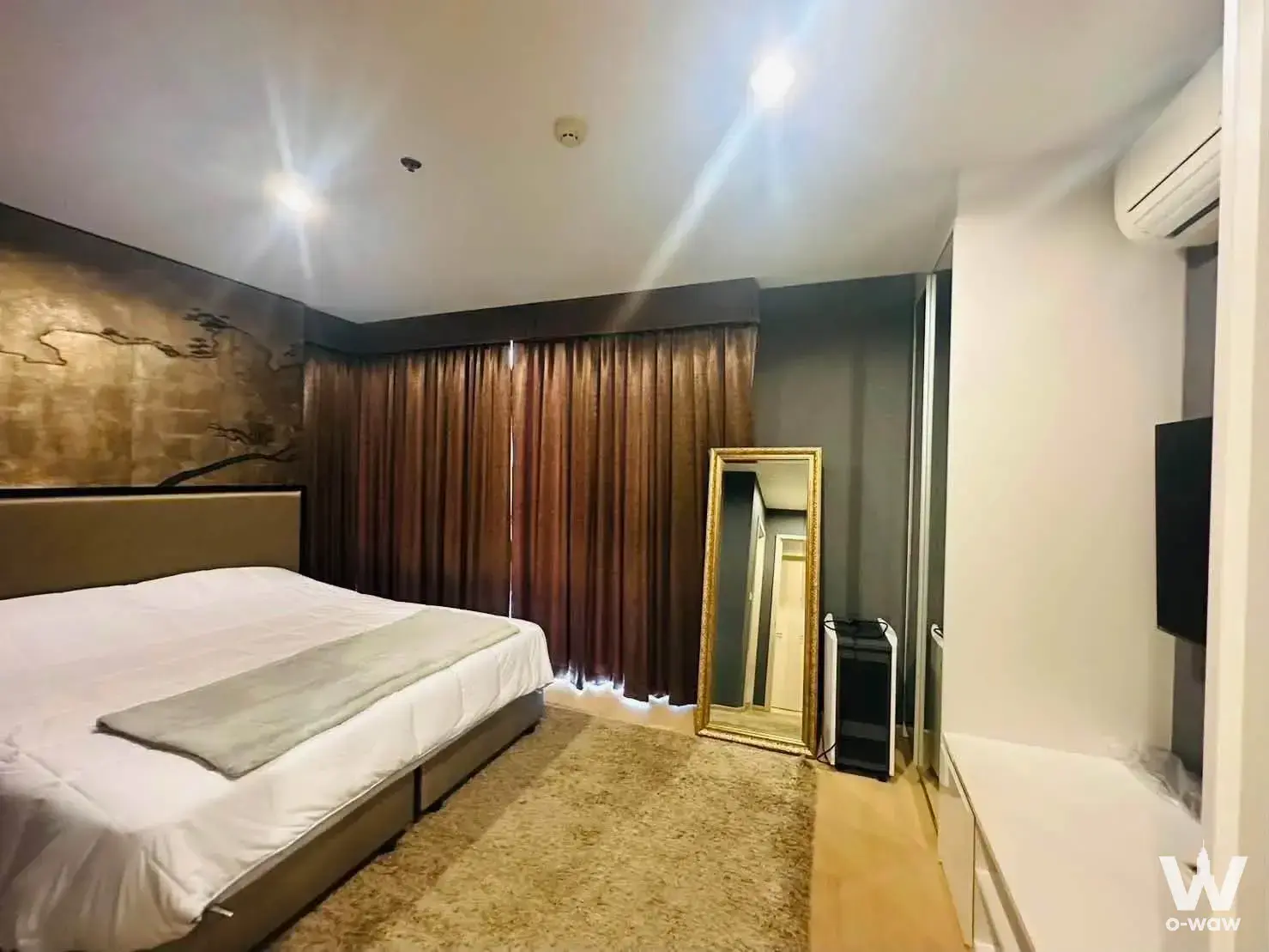 Modern bedroom in Rhythm Sukhumvit 42 condo featuring a gold metallic feature wall with dark branch mural