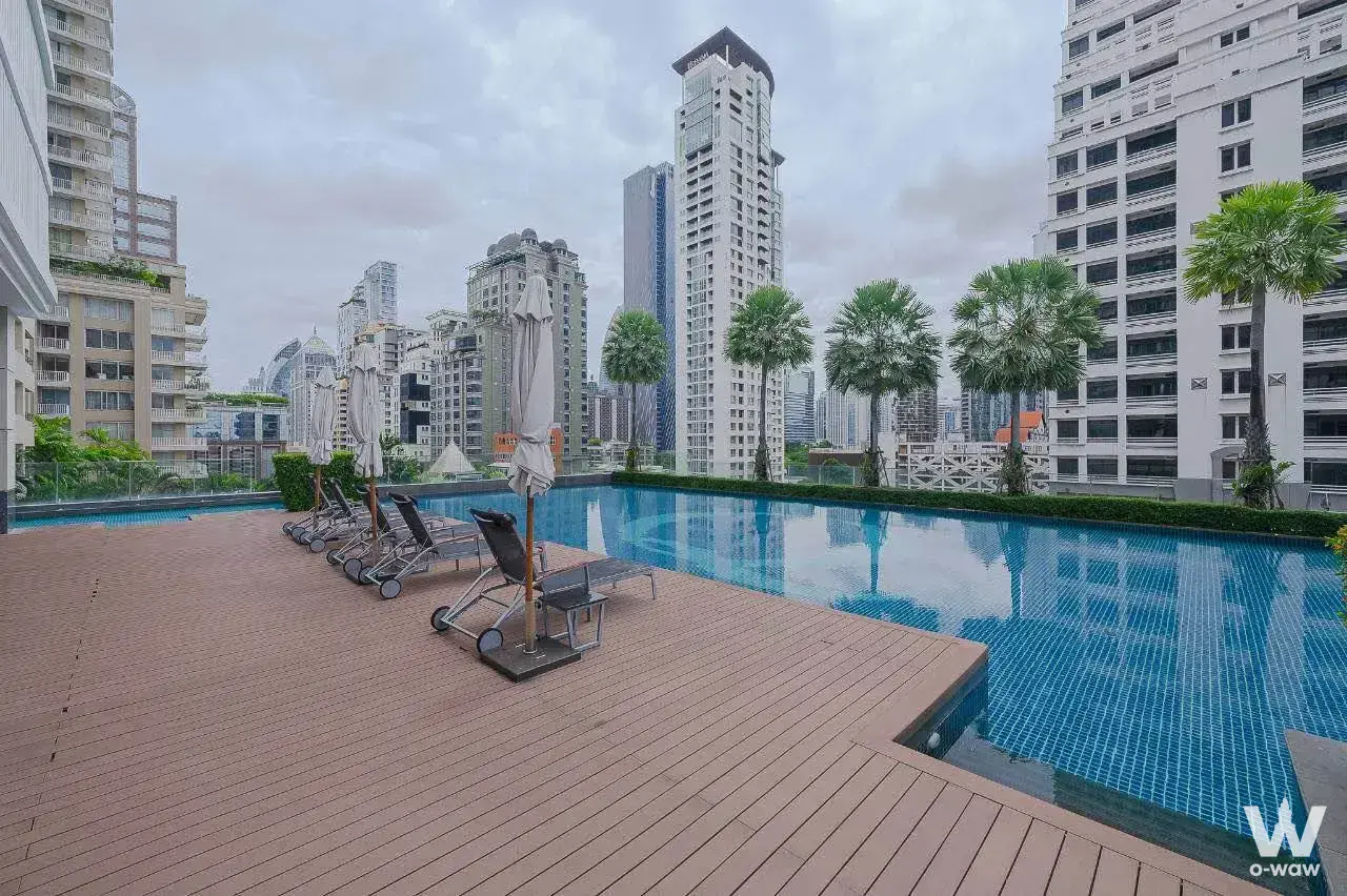Rooftop infinity pool with lounge chairs and city skyline views at a 2-bed condo for rent in Q Lang Suan