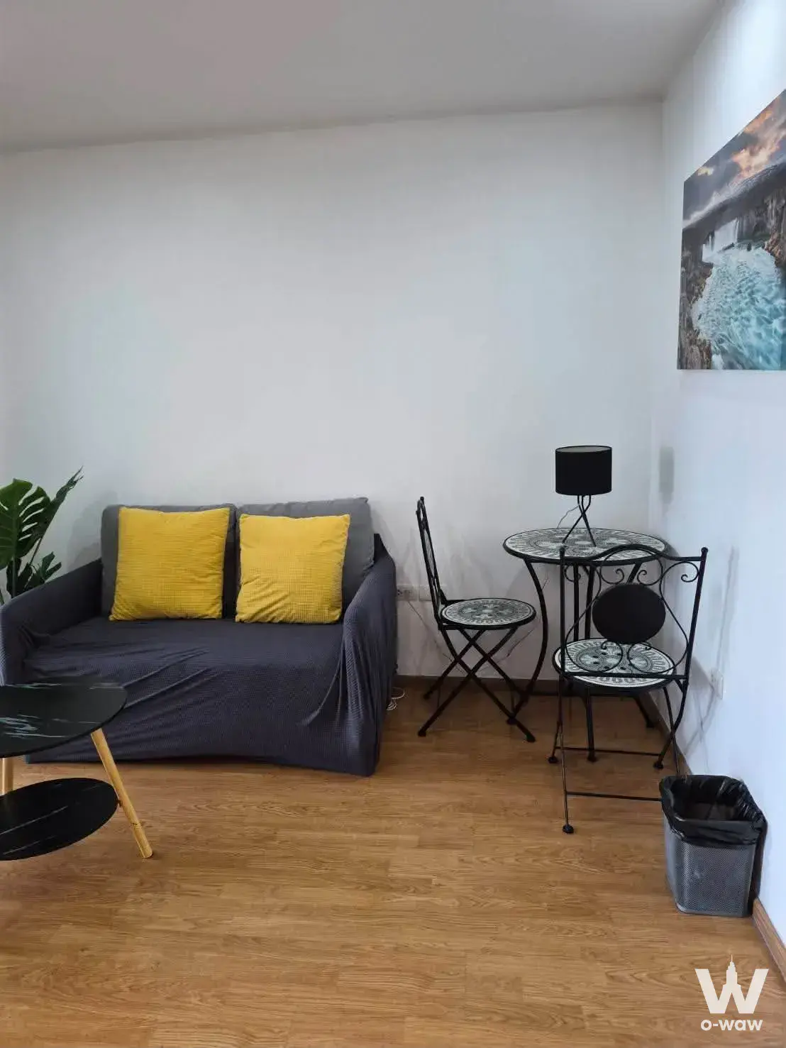 1-bed condo for sale in U Delight @ Onnut Station showing a compact living room with a grey sofa, mustard pillows, and