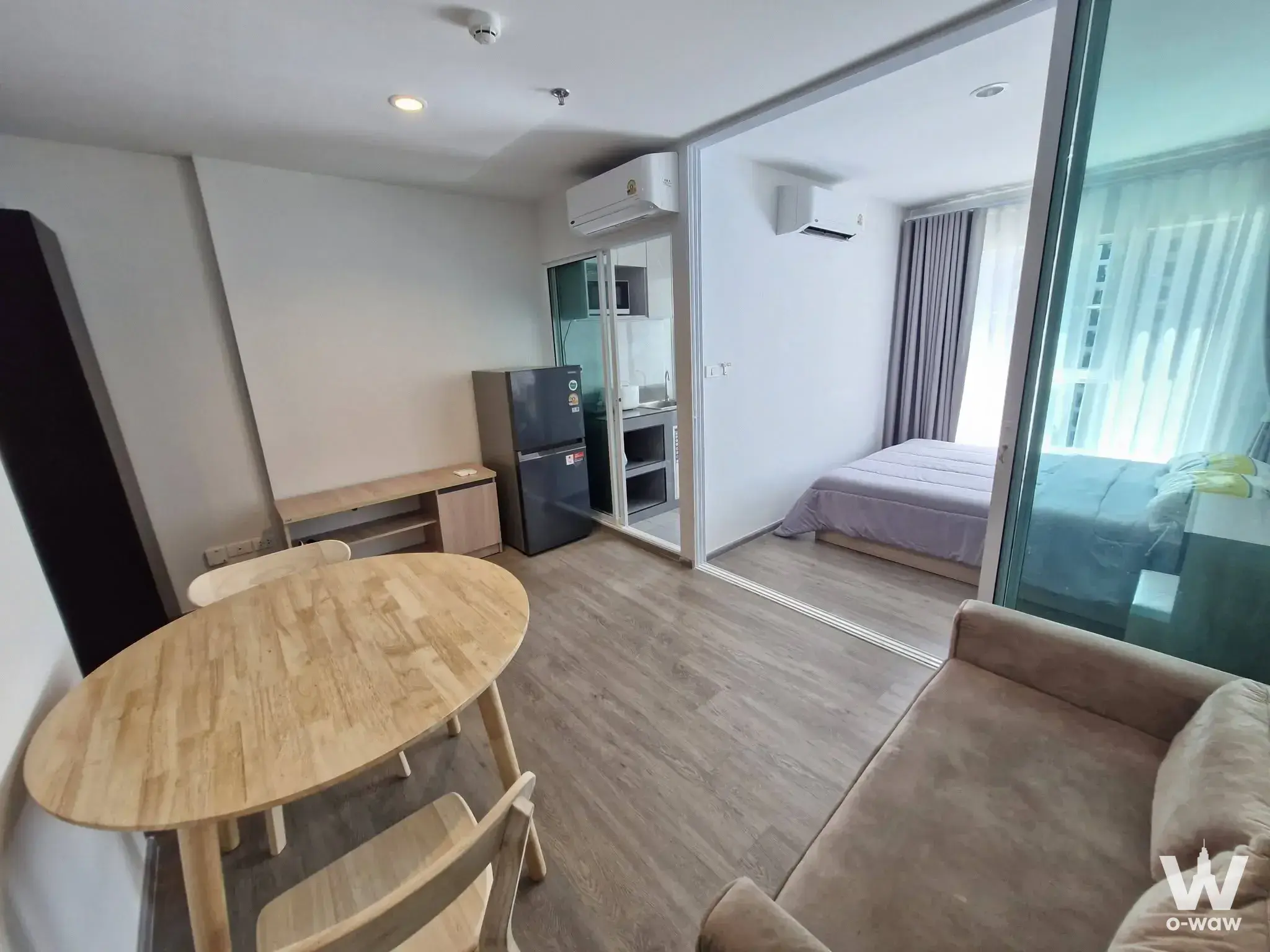 Open-plan studio with dining area and glass-partitioned bedroom in Regent Home Bangna 1-bed condo