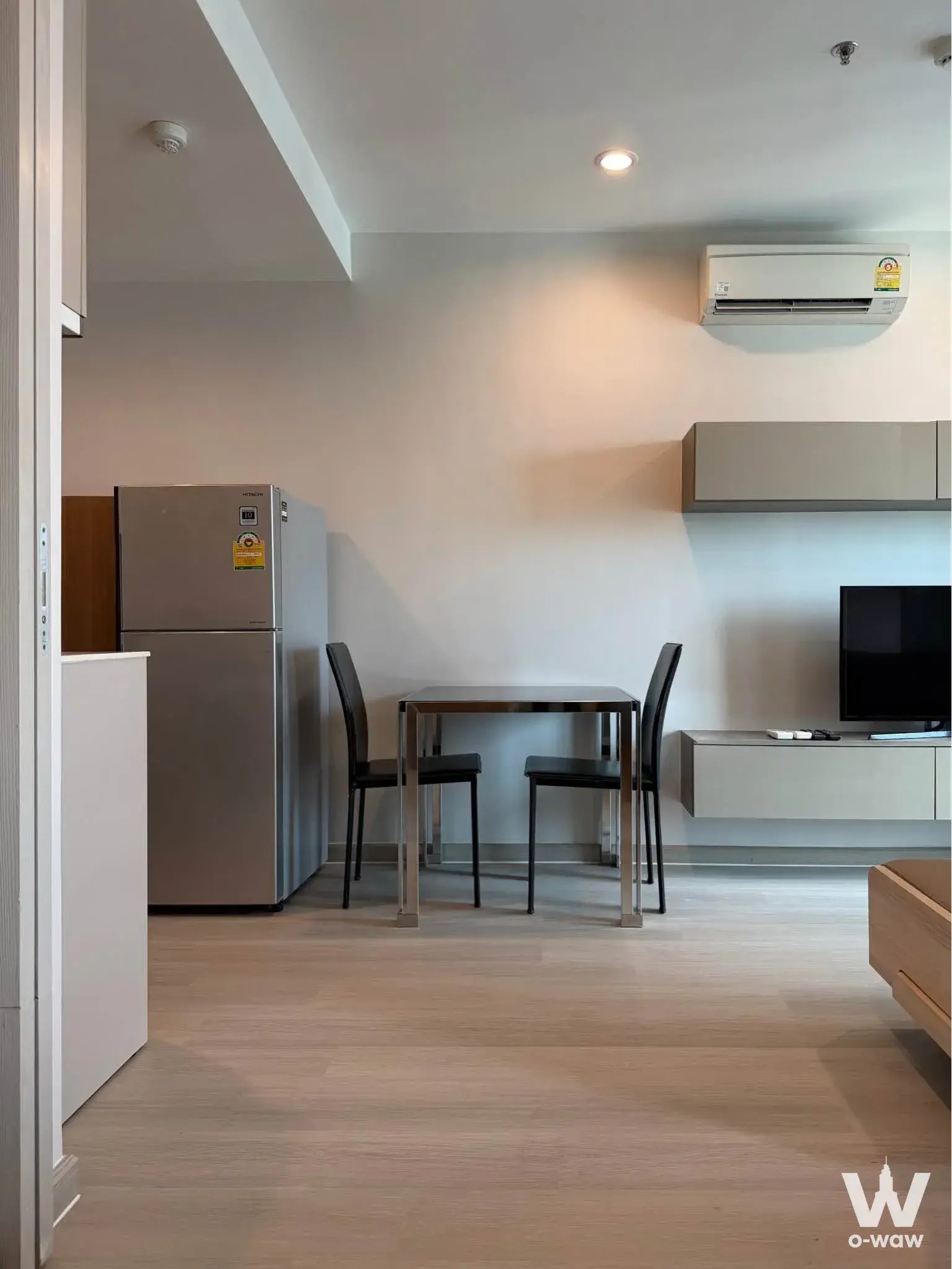 Ideo Q Chula-Samyan 1-bed condo living area with light wood flooring and minimalist grey accents