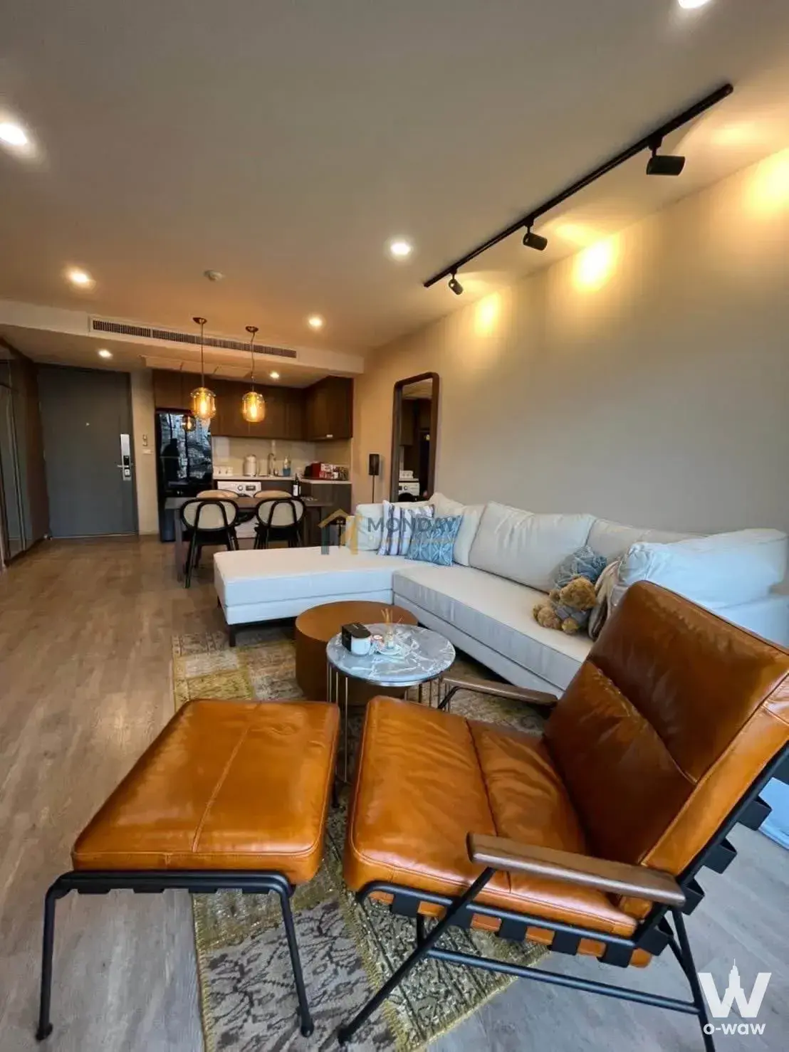 Noble Above Wireless-Ruamrudee 1-bed condo living room with grey sectional sofa and marble side table