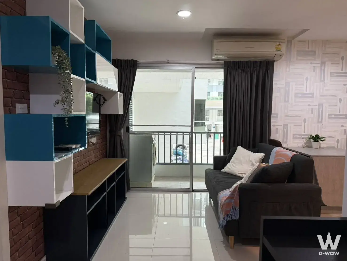 Punnawithi 2-bed condo living room featuring exposed red brick wall and sofa