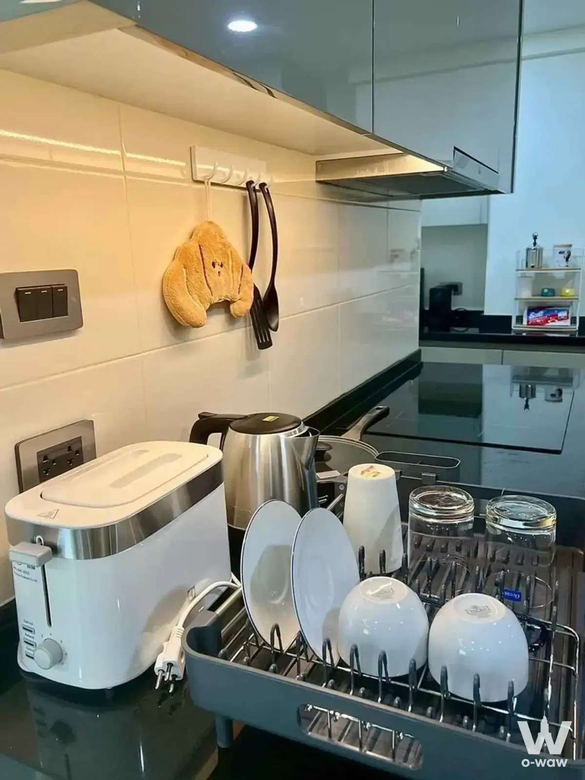 Tidy compact kitchen in a Belle Grand Rama 9 condo featuring white gloss cabinets and black stone counter