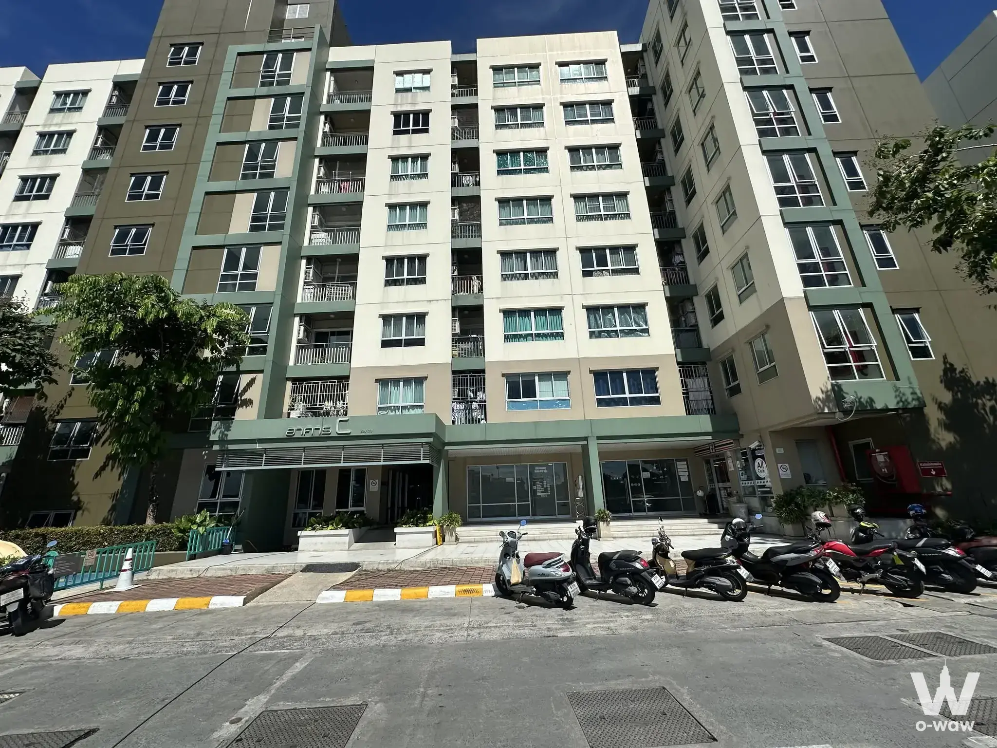 Beige and green exterior of Lumpini Ville Ramkhamhaeng 44 condo with ground-floor lobby and parking