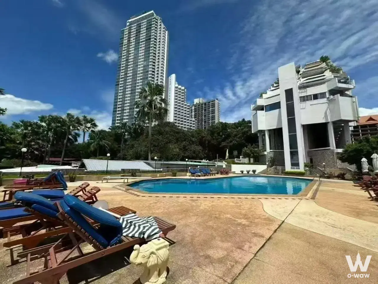 The kidney-shaped pool has lounge chairs and tropical greenery at Siam Penthouse Condominium 3