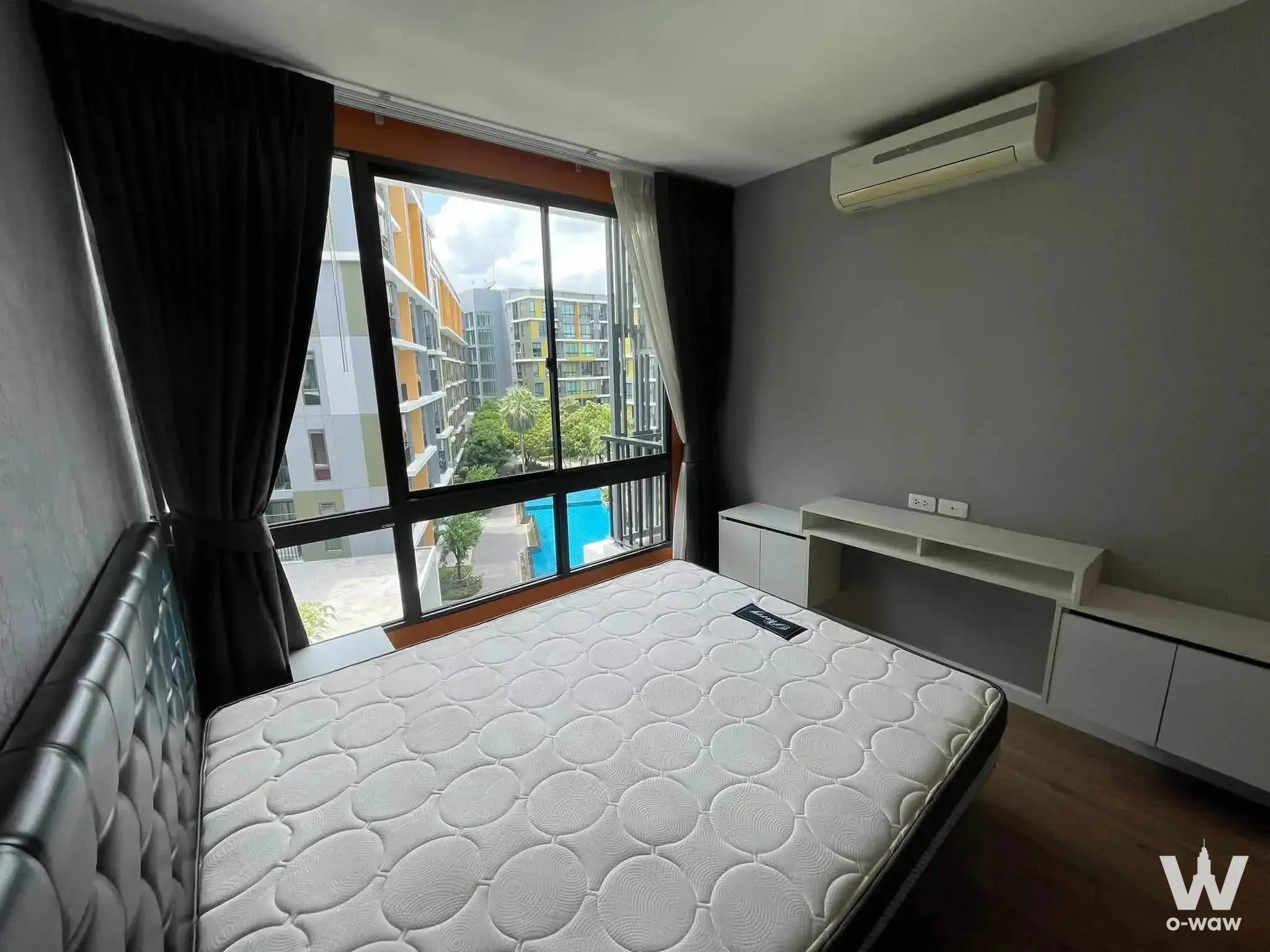 Bedroom in iCondo Sukhumvit 103 with pool view, desk, and minimalist modern furnishings