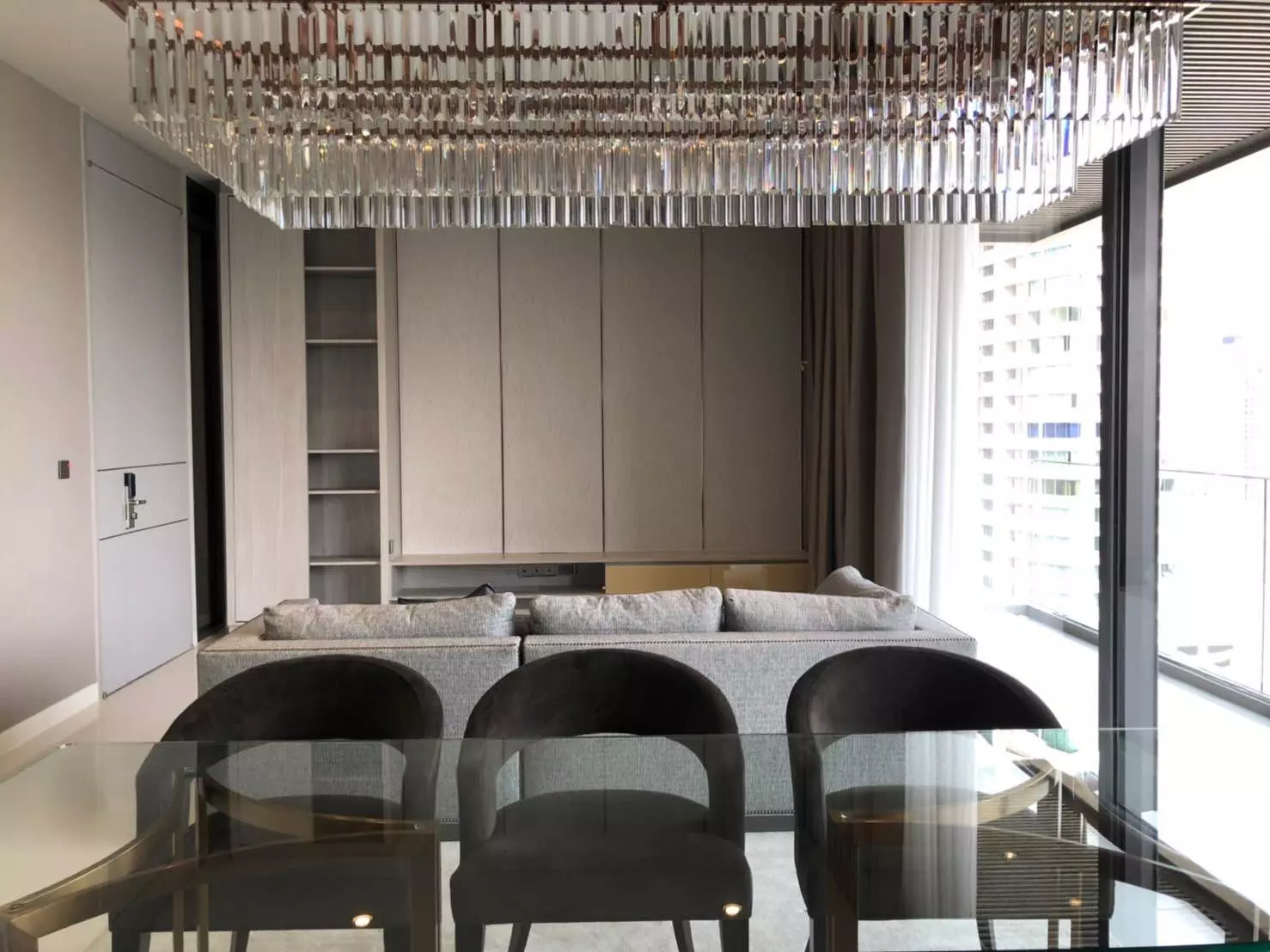 Luxury dining area in a VITTORIO Sukhumvit 39 condo showcasing a crystal chandelier and gold-framed table with city views