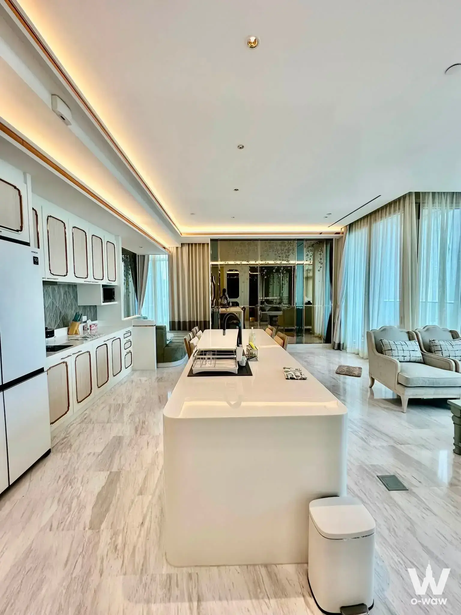 Open-plan kitchen in Four Seasons Private Residences condo featuring white island and grey backsplash
