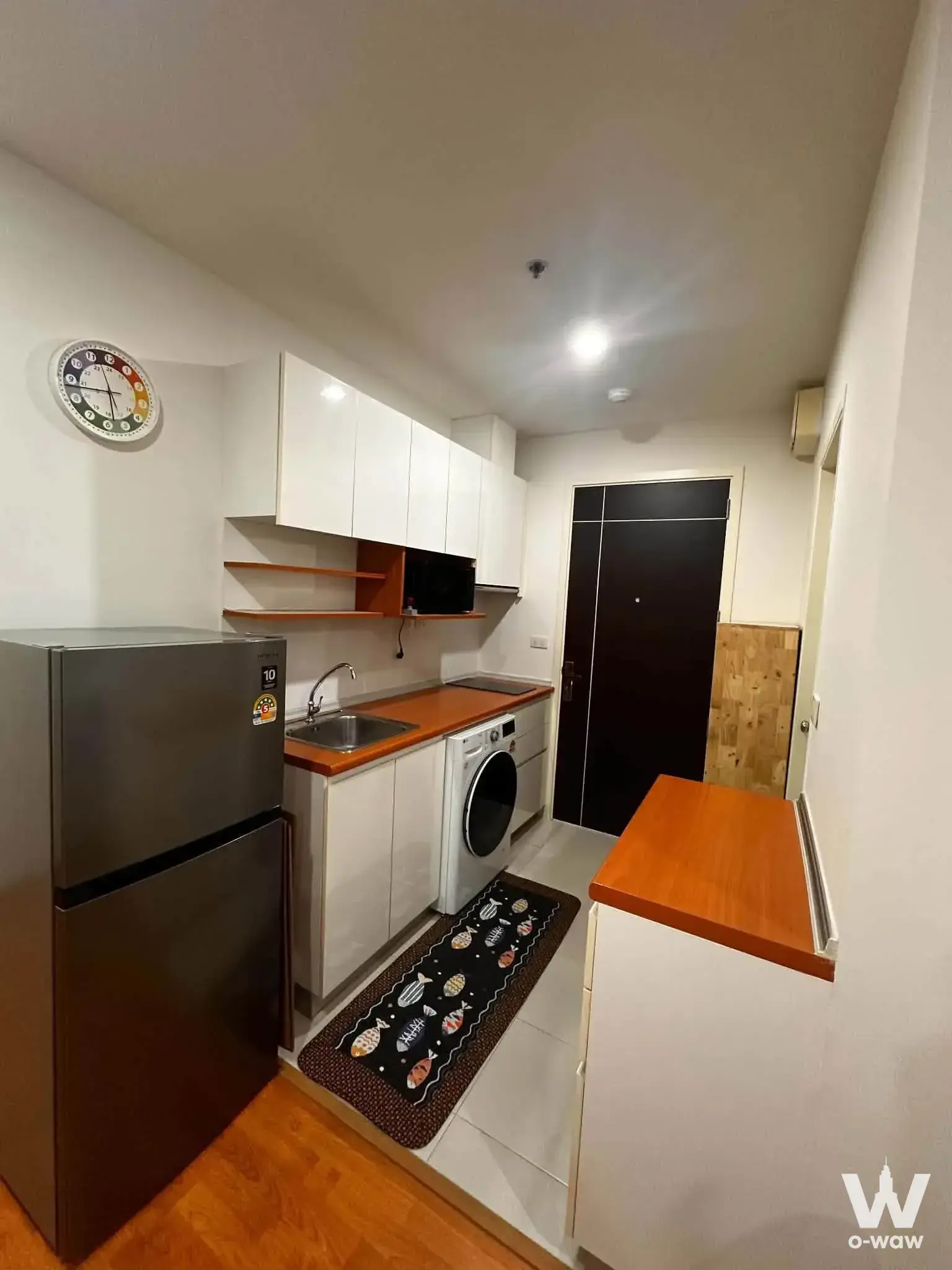Compact kitchenette in The President Sathon-Ratchaphruek 2 with white cabinets and wood-look counters
