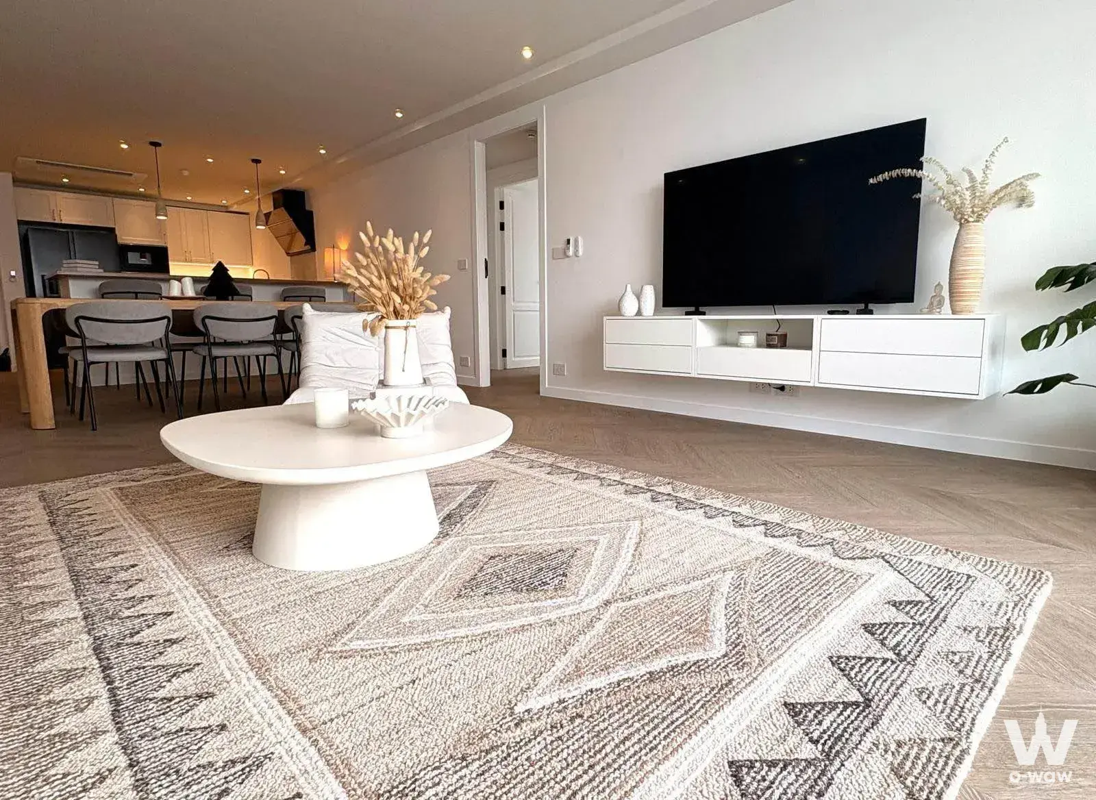Open-plan living room in a D.S. Tower 2 condo with herringbone floors and a beige geometric rug