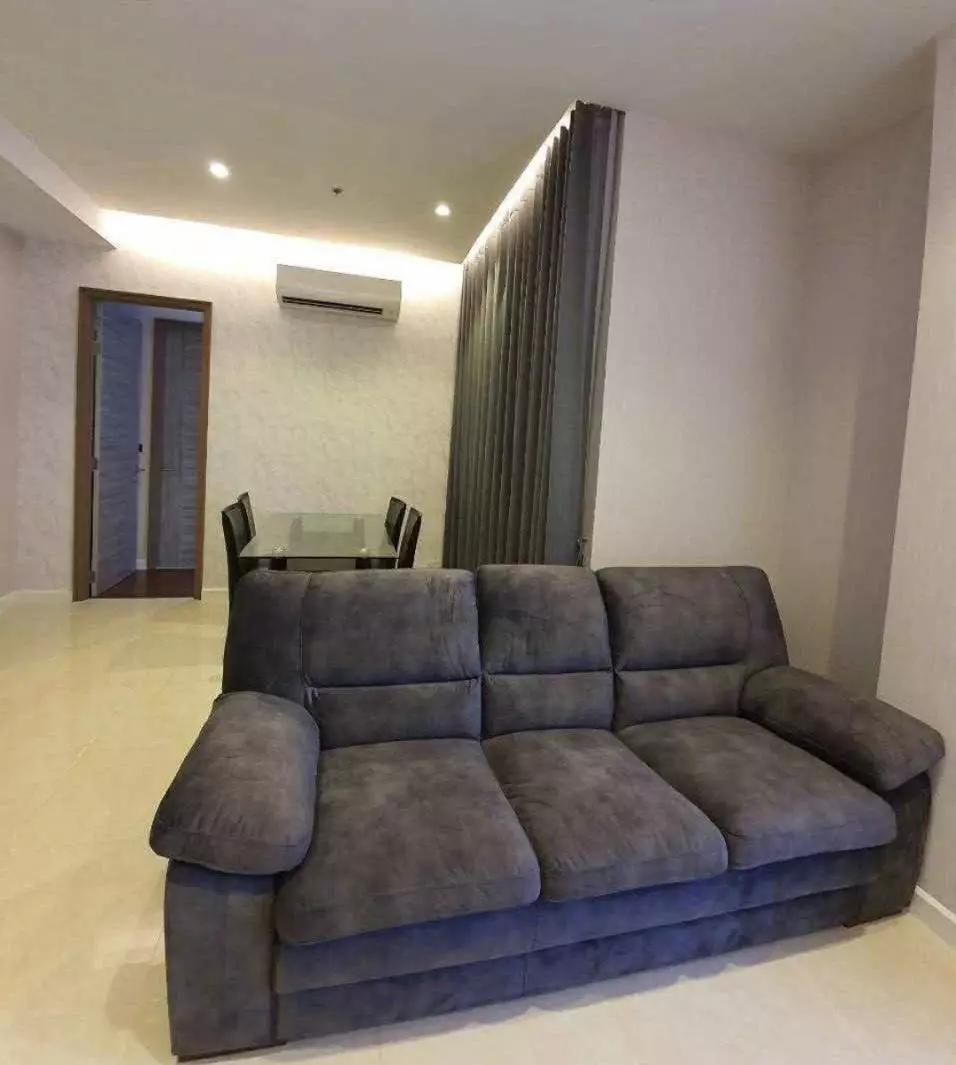 Living and dining area featuring a dark grey sofa and glass table in a 2-bed condo at Mayfair Place Sukhumvit 50