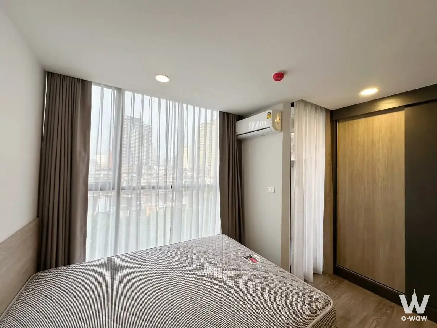 Bedroom for rent in FLEXI Sathon-Charoen Nakhon with city skyline view, oak wardrobe, and neutral palette